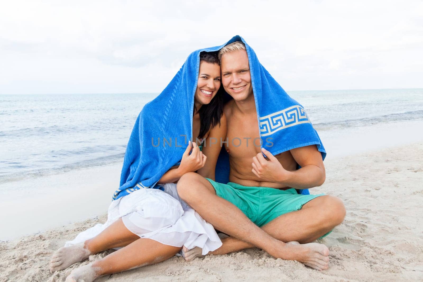 laughing young couple in love with a towel on the beach in summer holiday love leisure lifestyle