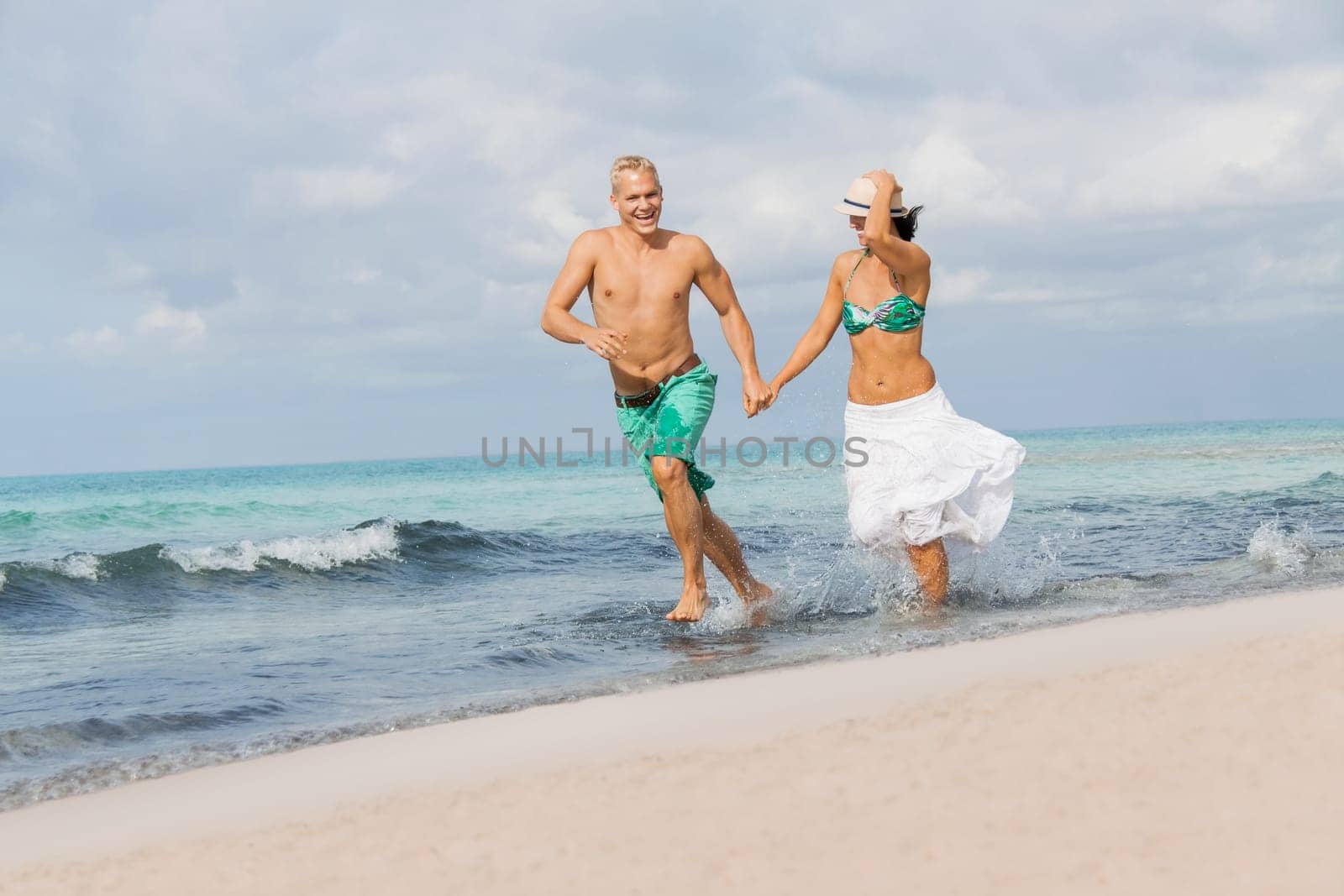 Young happy couple in love has fun on the beach in summer