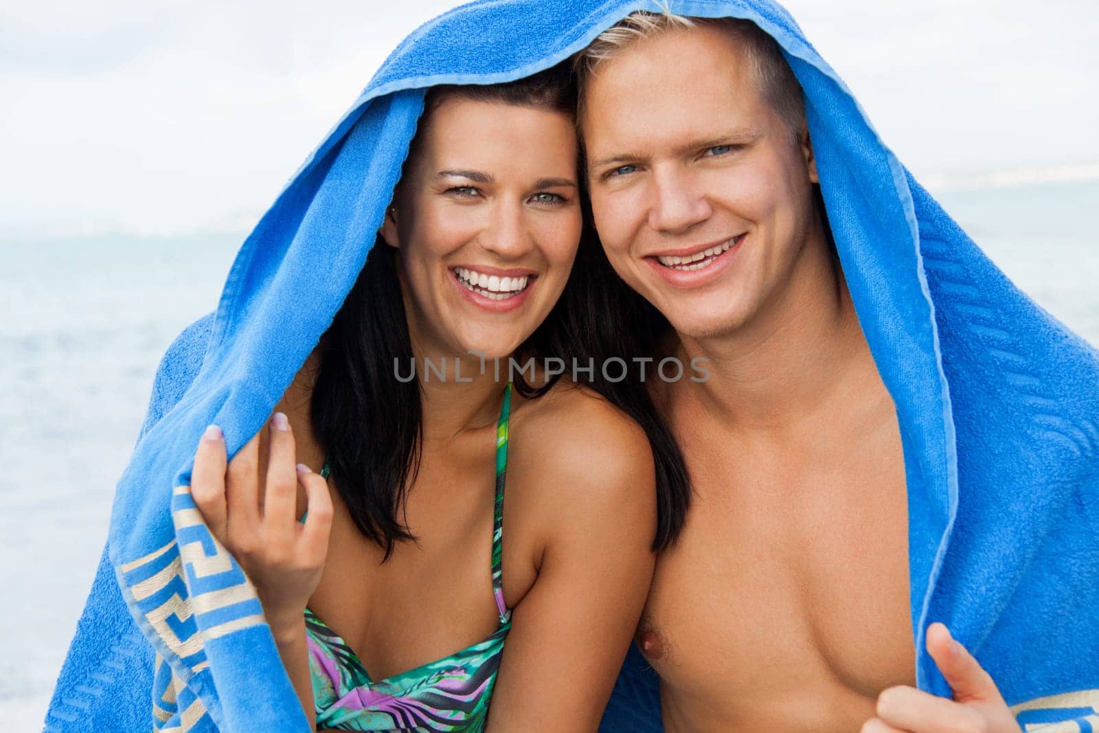 laughing young couple in love with a towel on the beach in summer holiday love leisure lifestyle