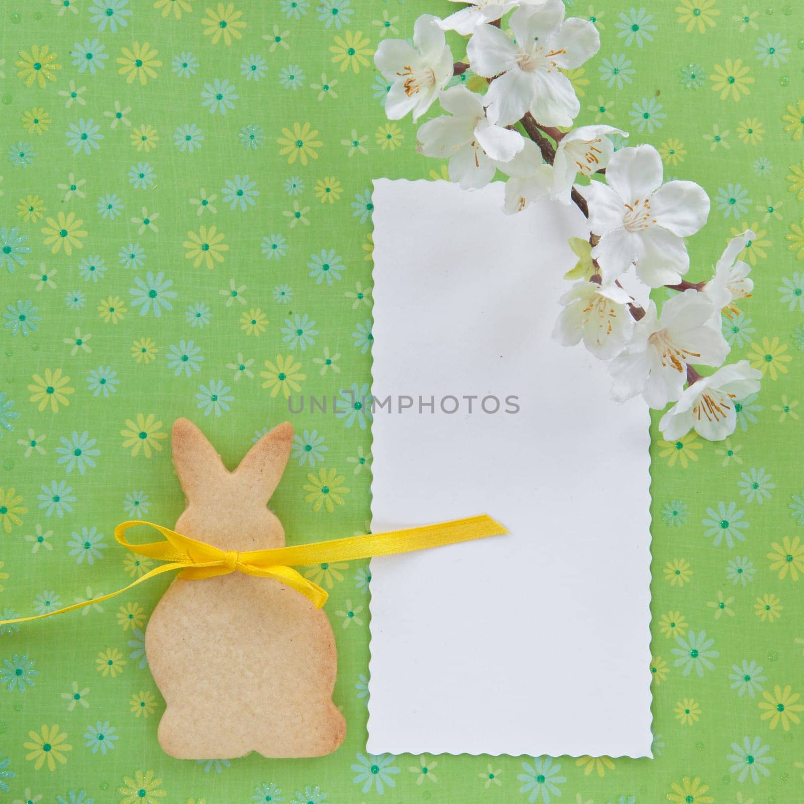 Colorful background with flowers and a cookie in the shape of an Easter bunny