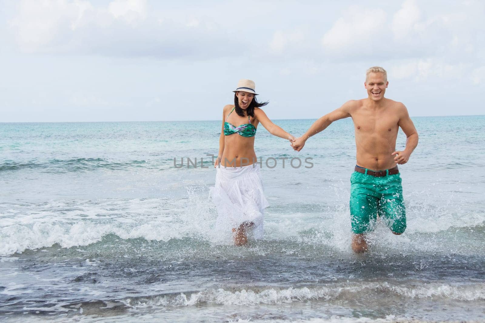 Young happy couple in love has fun on the beach in summer