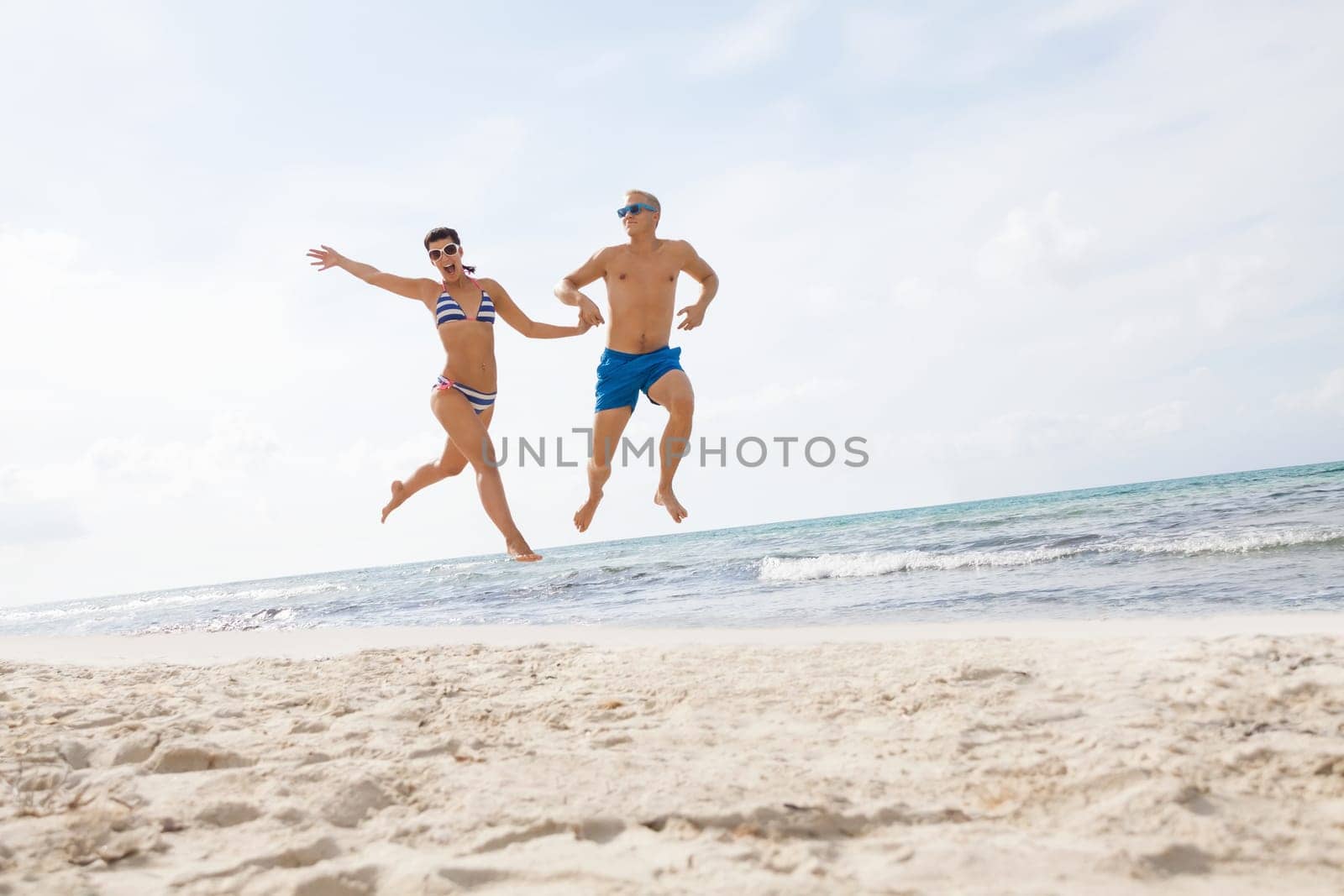 Young happy couple in love has fun on the beach in summer