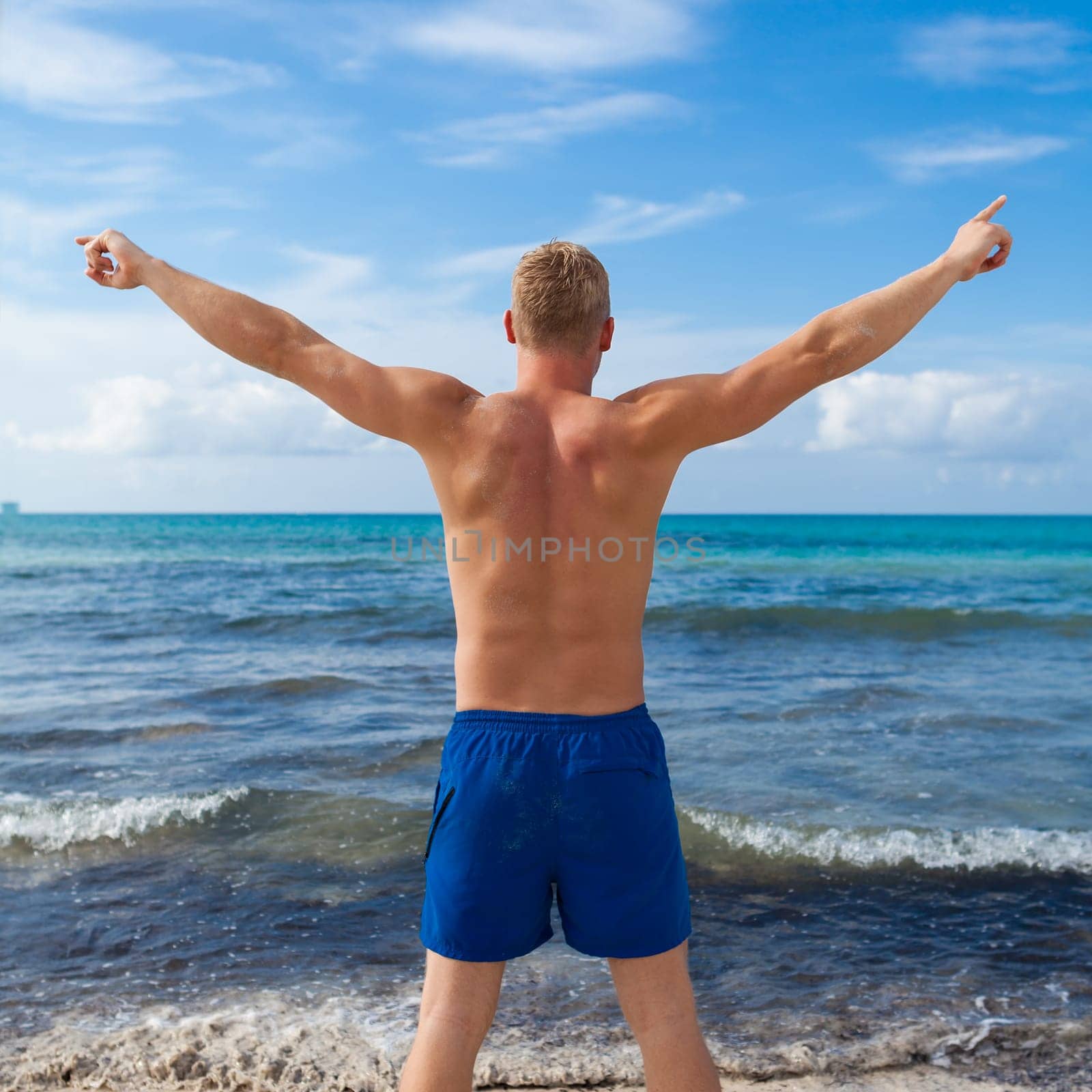 Sporty young man in swimming trunks on the beach on holiday summer leisure lifestyle