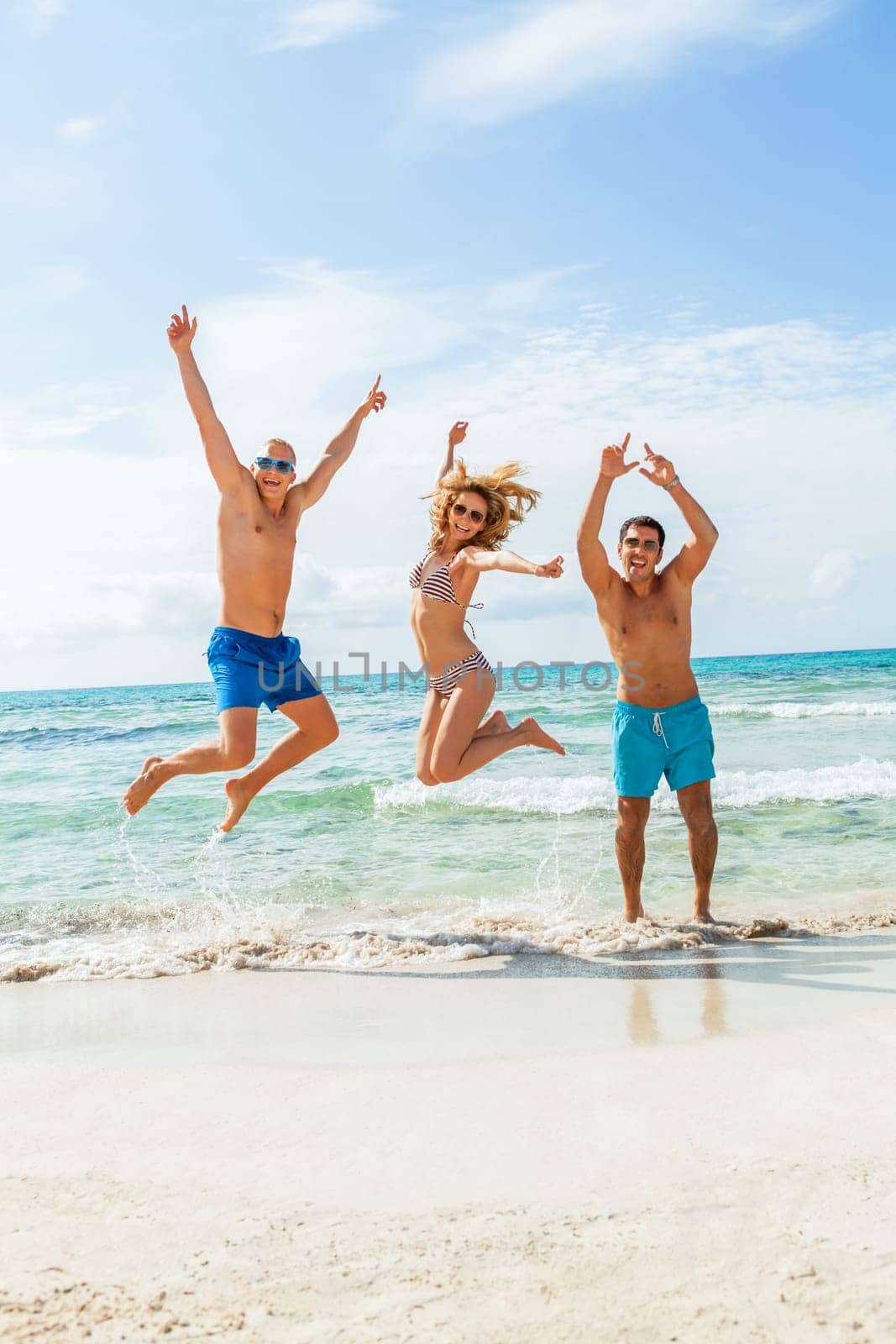 Group of laughing young people on the beach in summer holiday leisure lifestyle