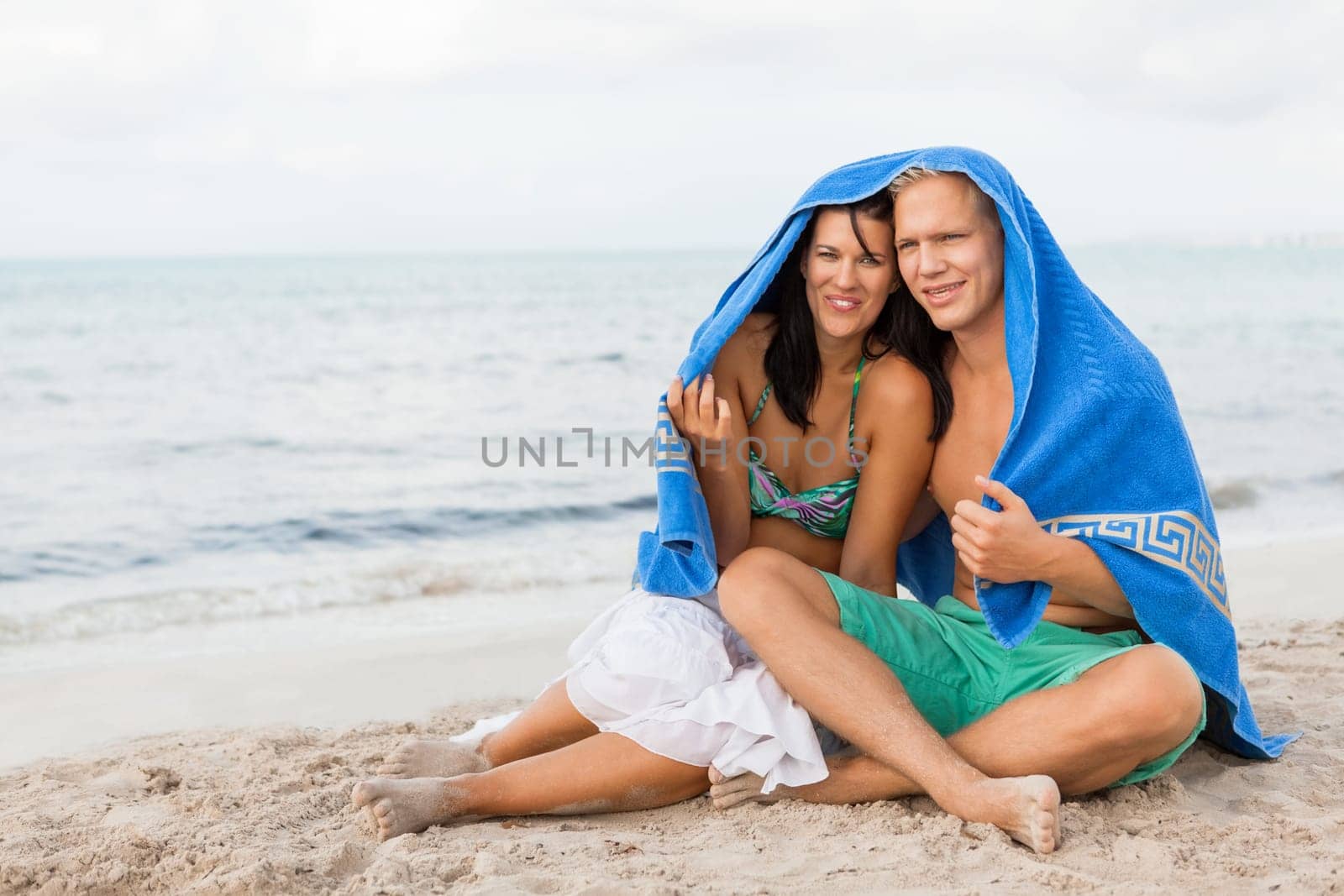 laughing young couple in love with a towel on the beach in summer holiday love leisure lifestyle