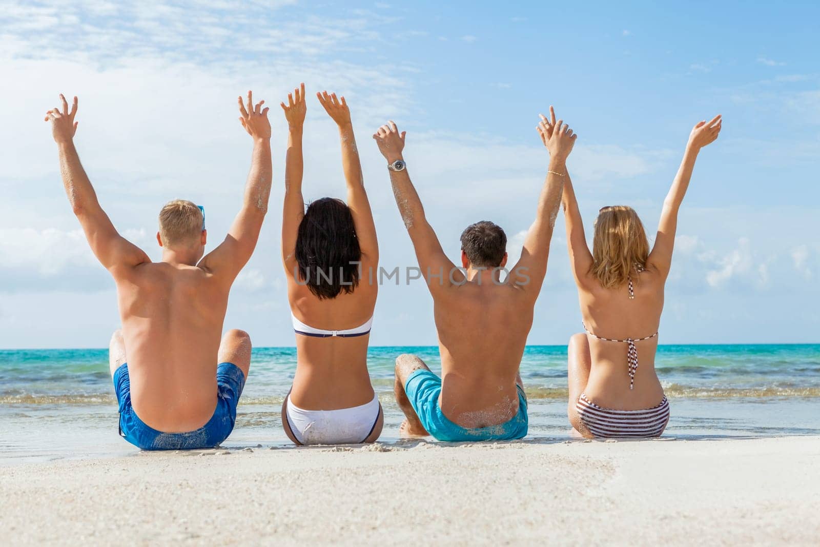 Group of laughing young people on the beach in summer holiday leisure lifestyle