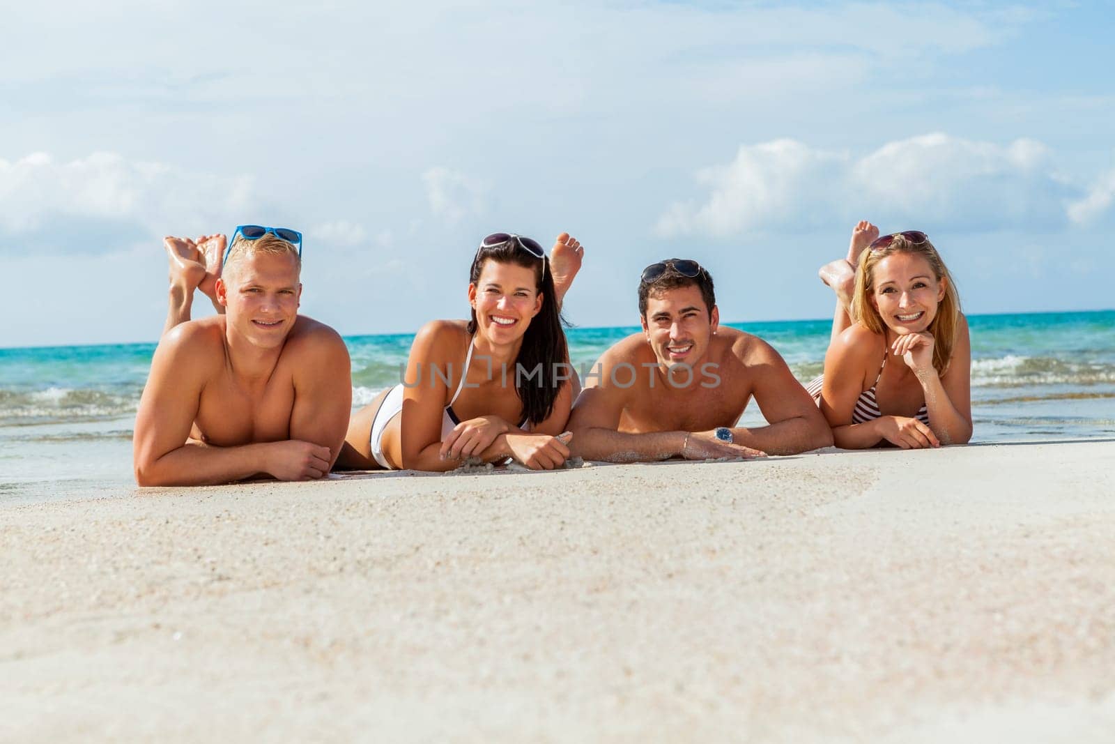 Group of laughing young people on the beach in summer holiday leisure lifestyle