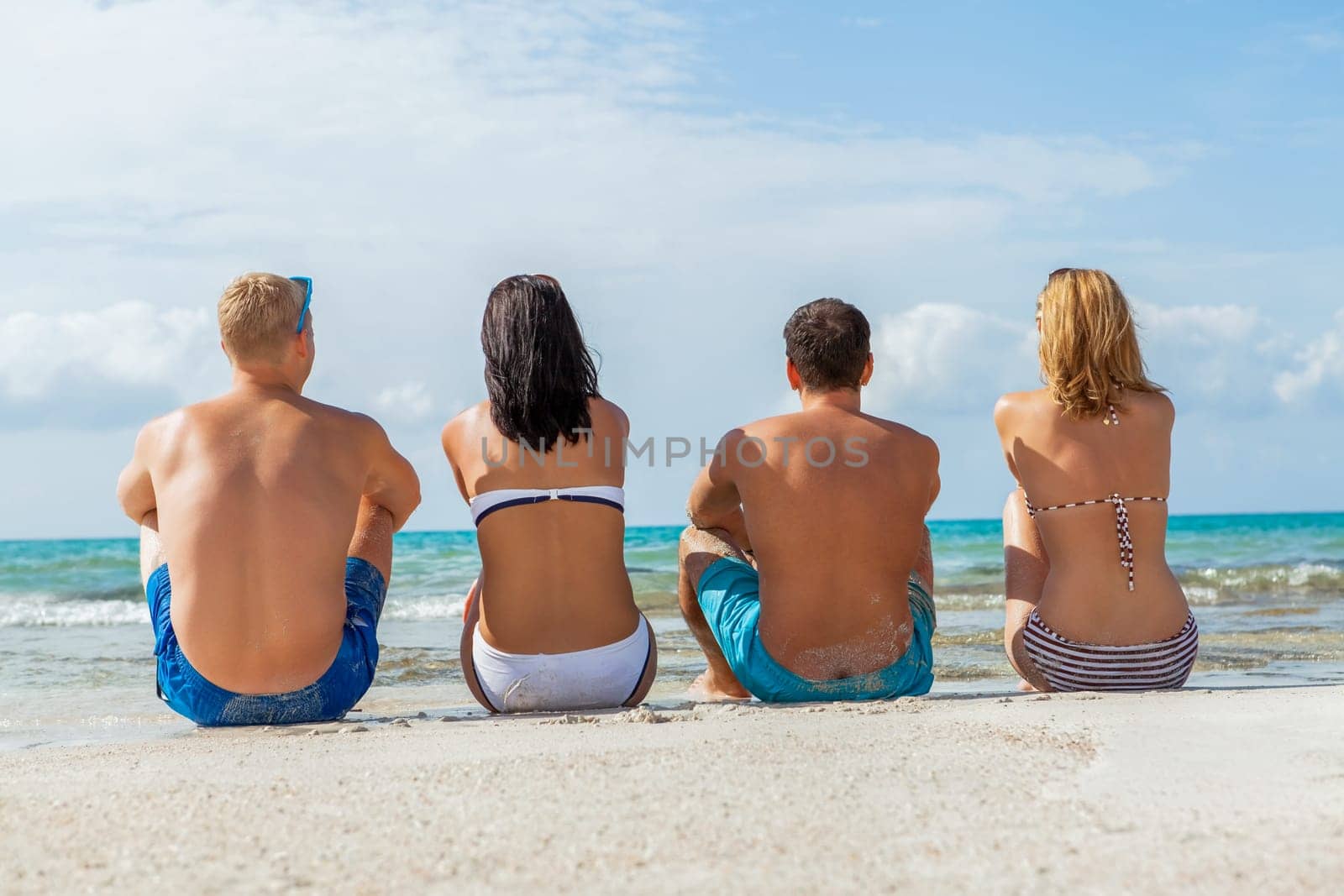 Group of laughing young people on the beach in summer holiday leisure lifestyle