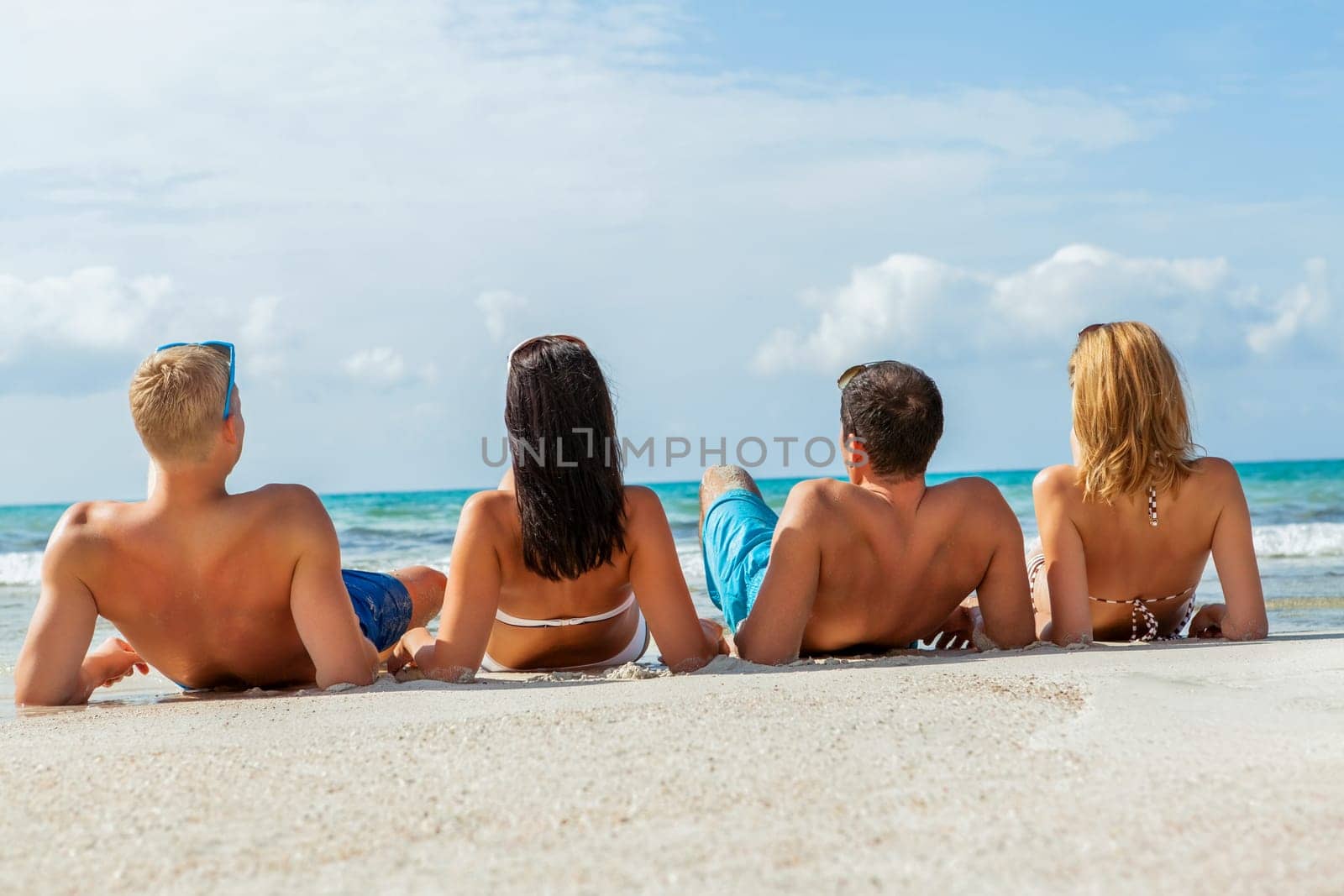 Group of laughing young people on the beach in summer holiday leisure lifestyle