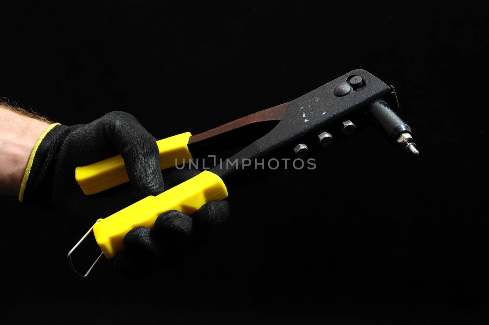 Rivets Pliers and Hand on a Black Background