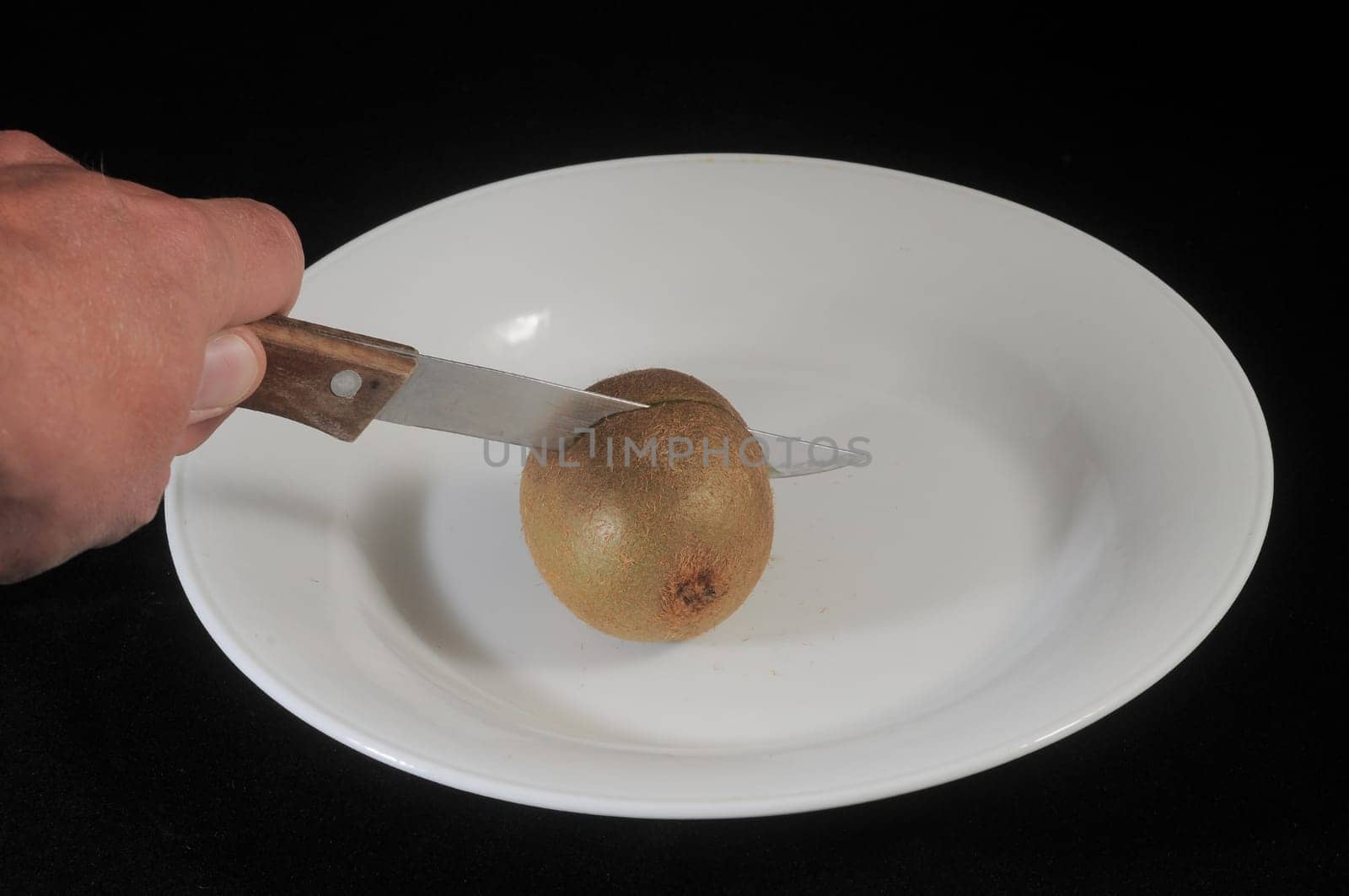Cutting a Green and Brown Kiwi in Two Parts