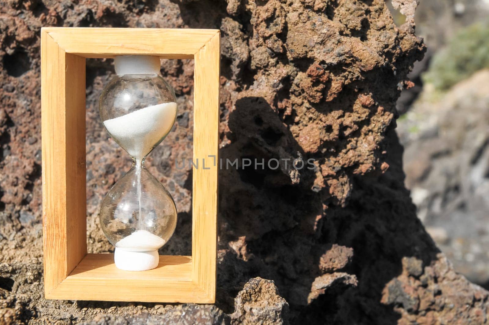 Time Concept White Sand Hourglass on the Volcanic Rocks