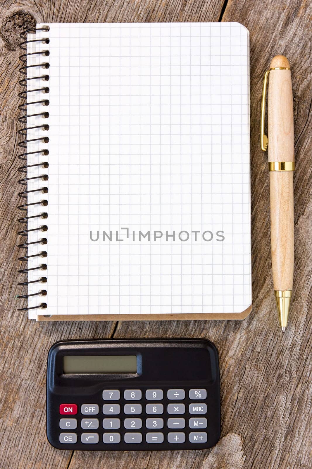 Adding up figures concept with calculator, pen and notebook on the wooden background