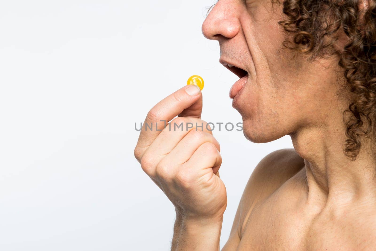 Cropped shot of bare chested mediterranean man taking colourful pill
