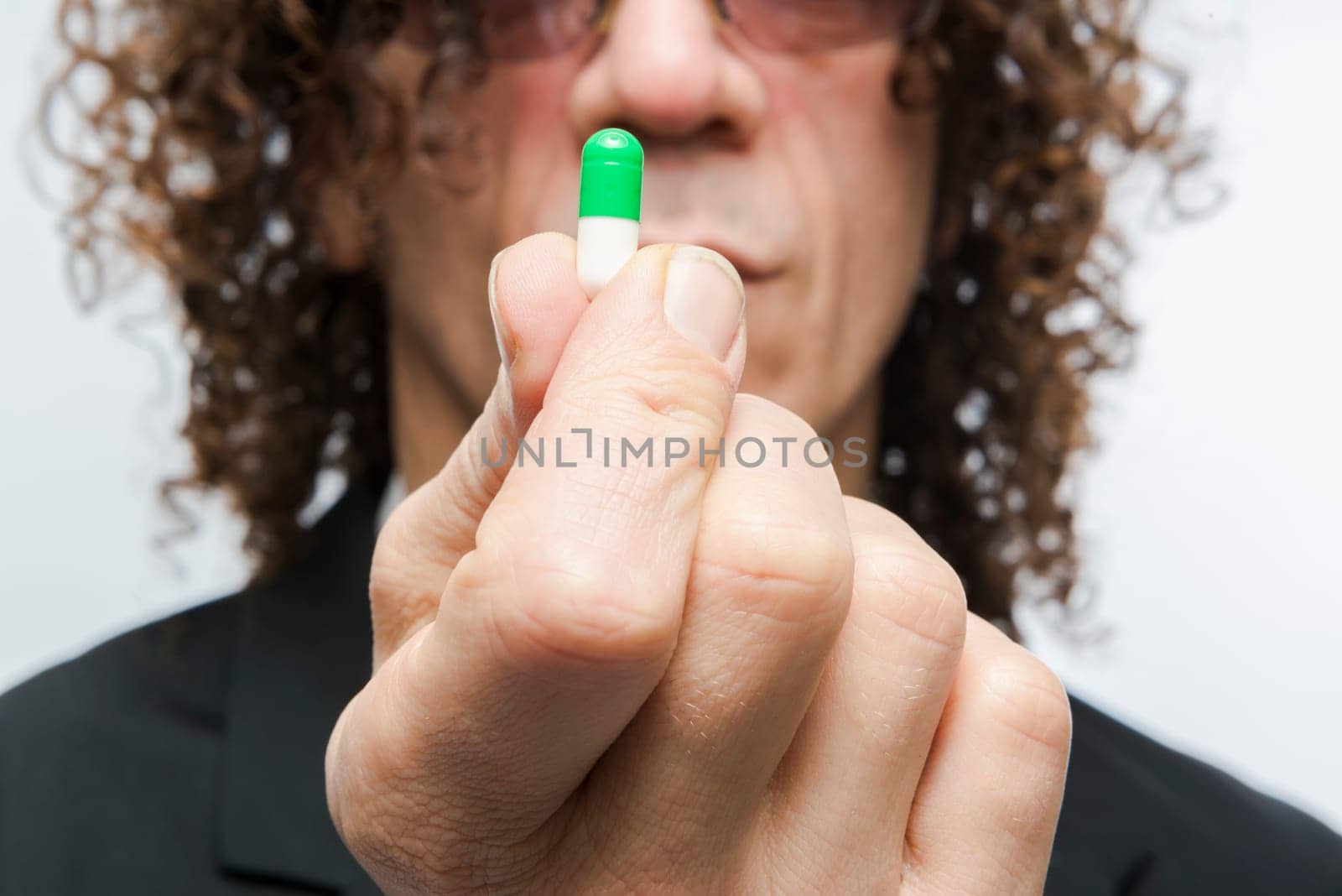 Cropped shot of mediterranean man in a suit holding colourful pill