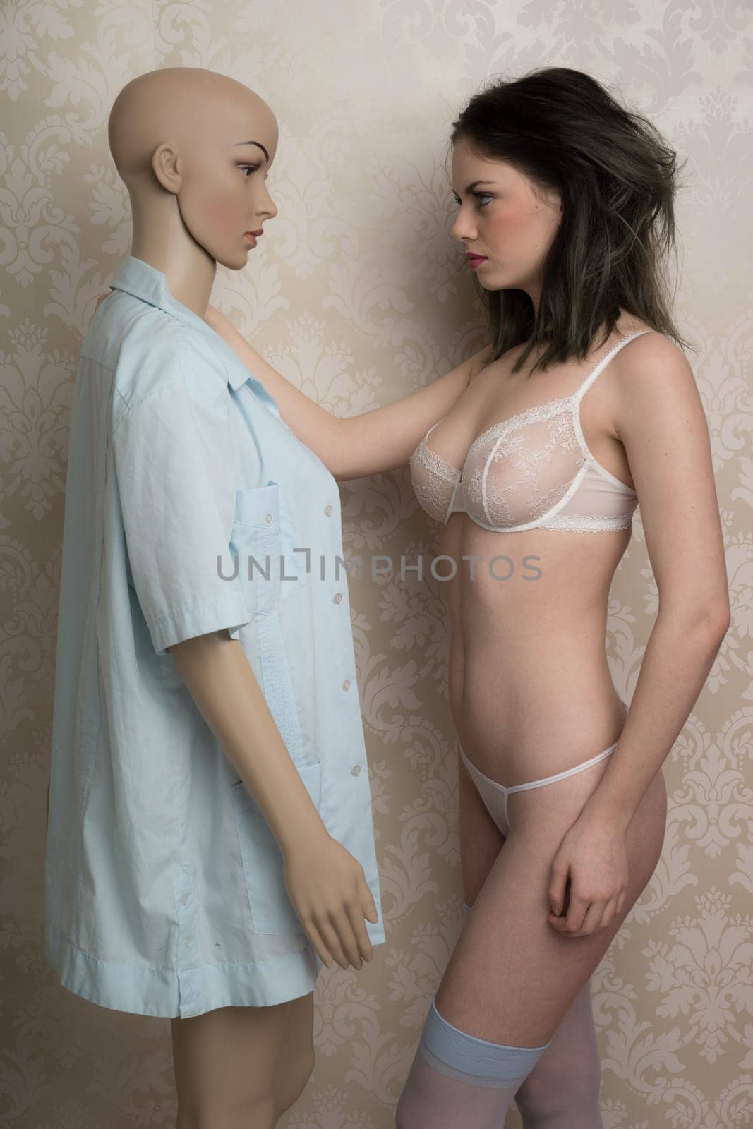 Beautiful woman modeling a sexy see through bra standing with a mannequin in lingerie