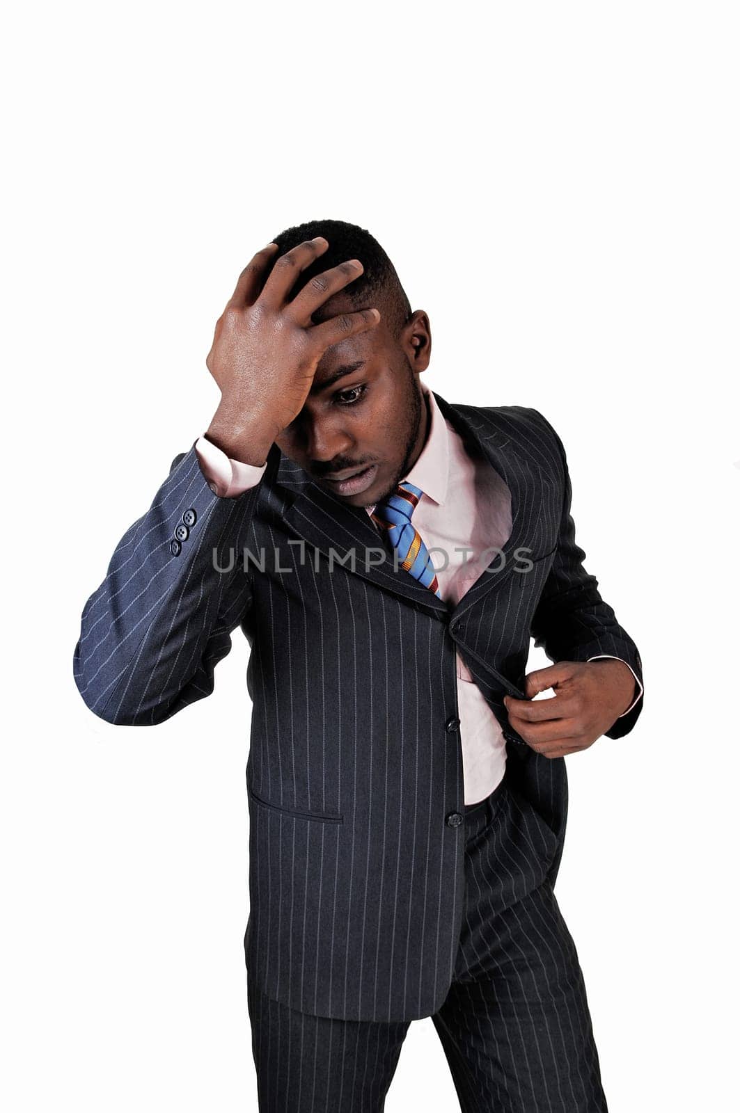 A black young man standing for white background with his hand on his head.looking desperate..