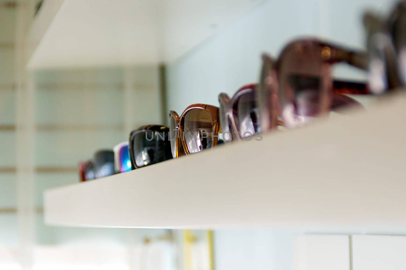 shelf on wall with an assortment of generic sunglasses with shallow depth of field.