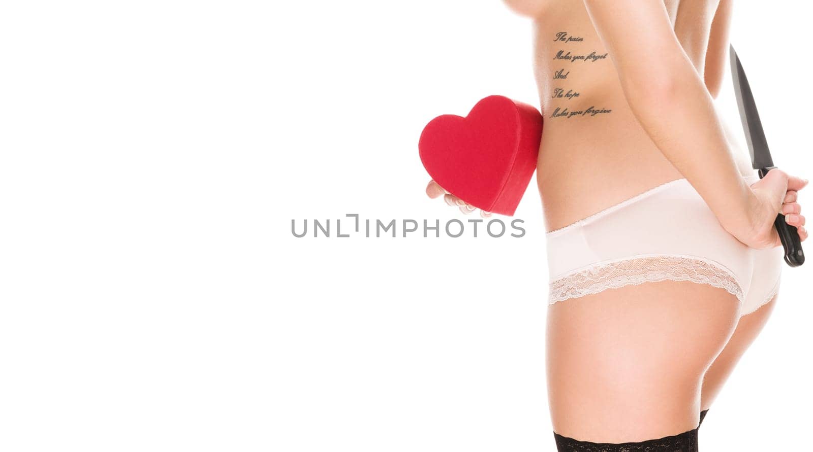Young woman in lingerie holds red heart in front of her and knife behind her back