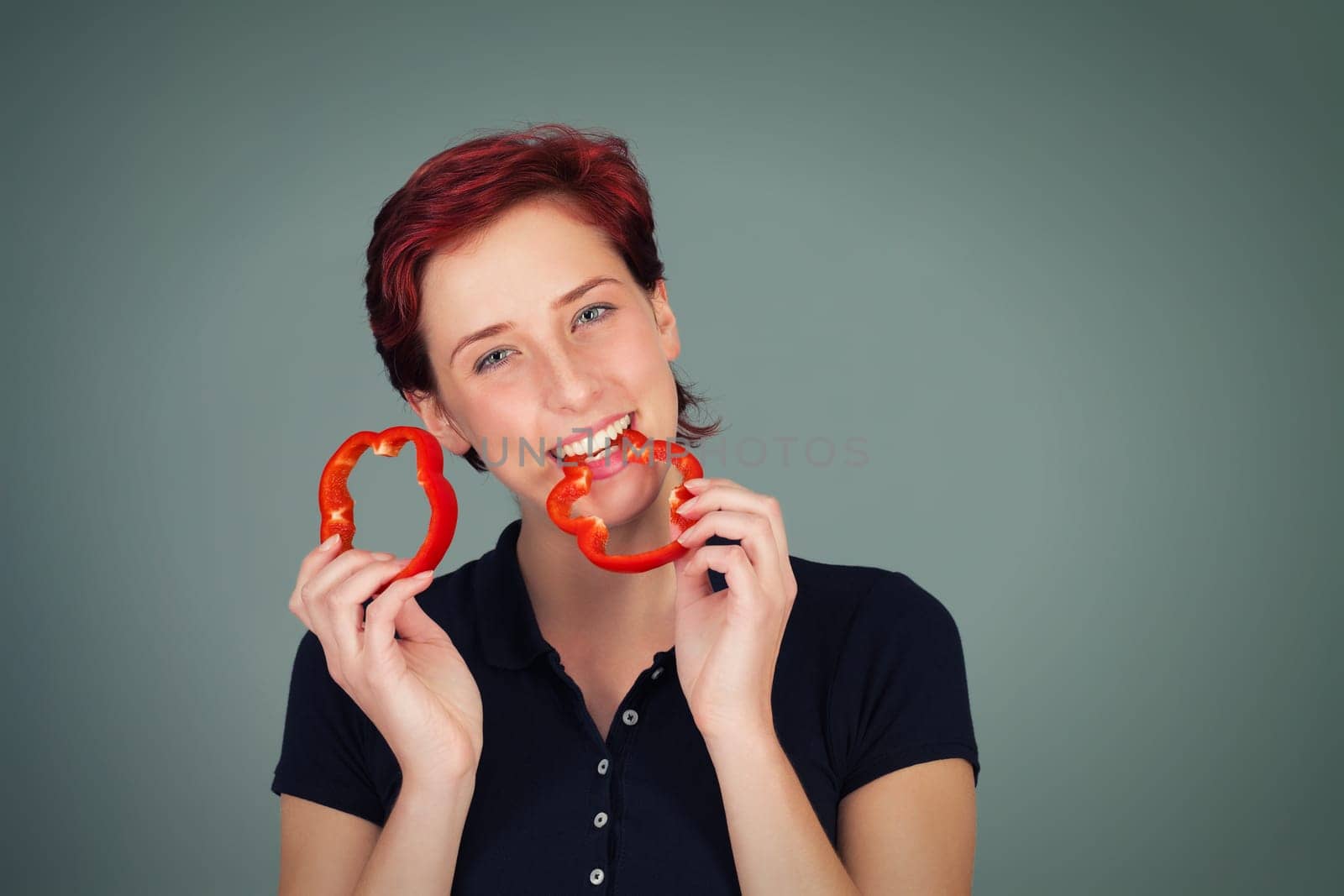 Young beautiful woman bites into a red slice of pepper
