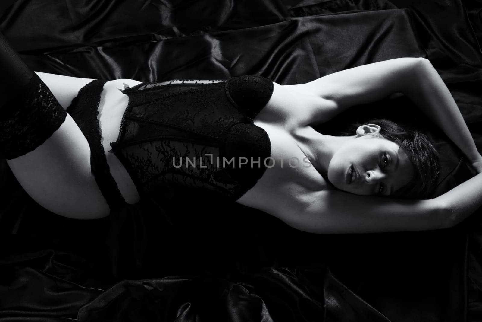 Young beautiful sensual woman wears corsage in bed
