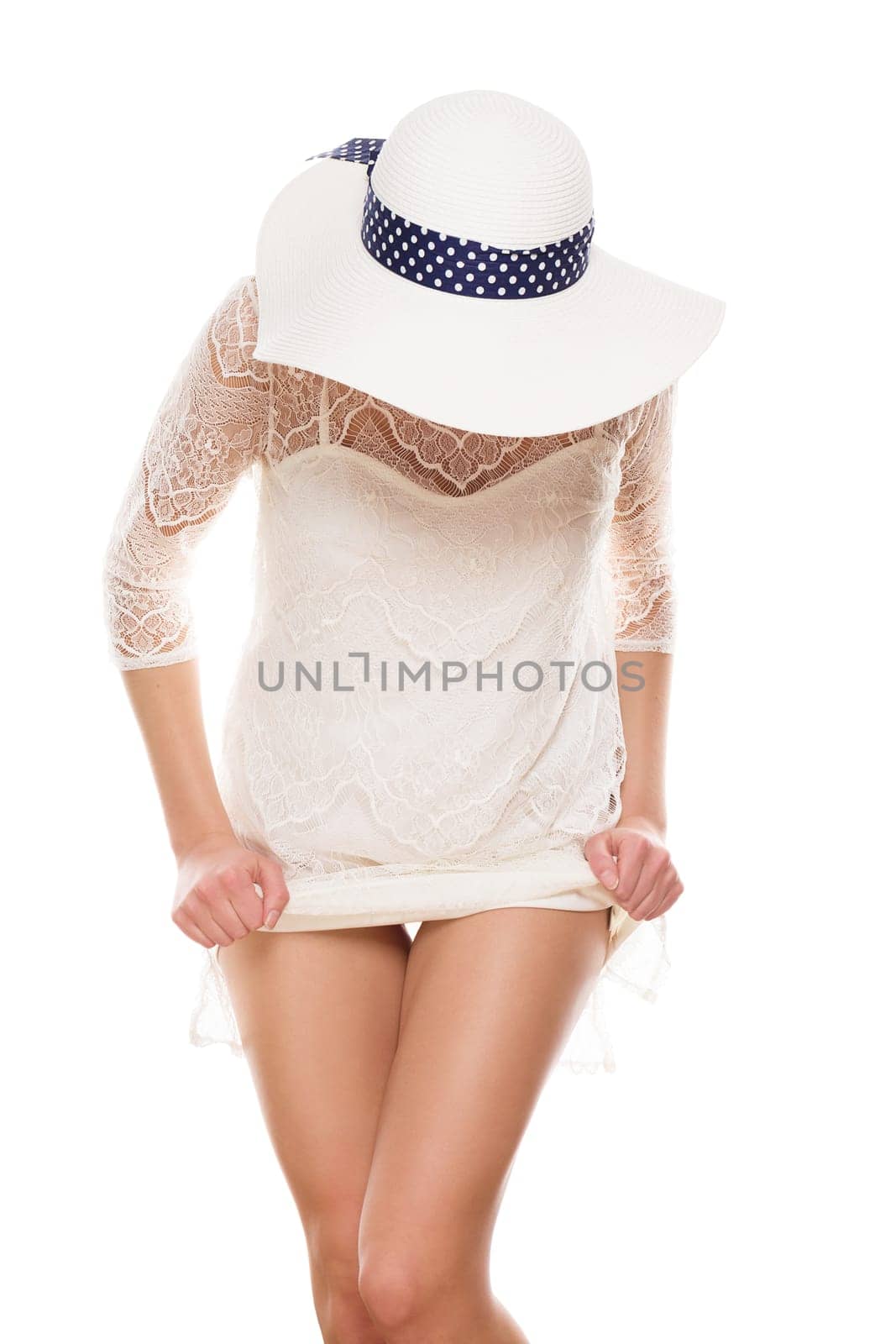 Young woman with sun hat lifts her dress and shows legs against a white background