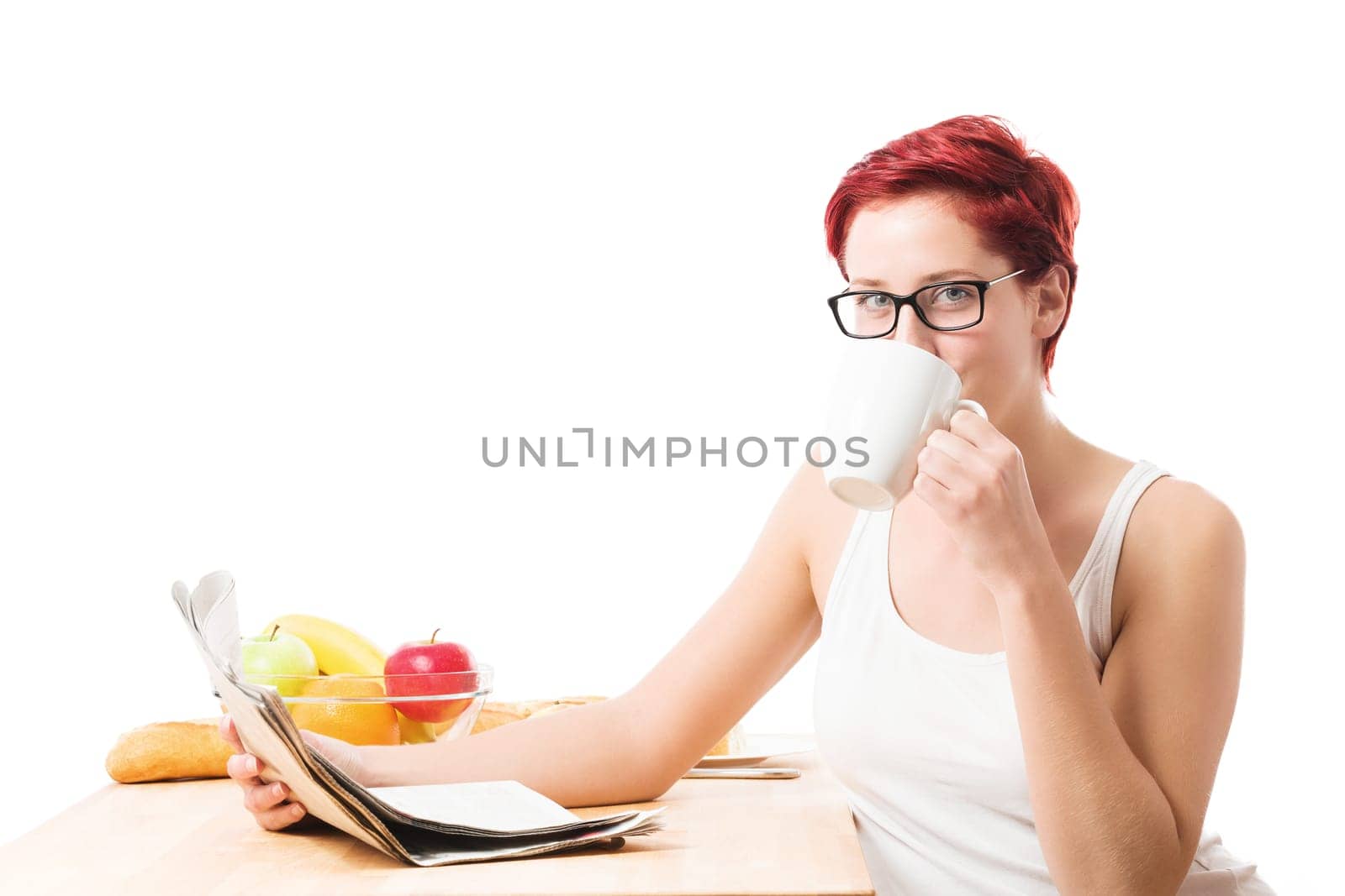Young woman having breakfast with coffee reading the newspaper against a white background