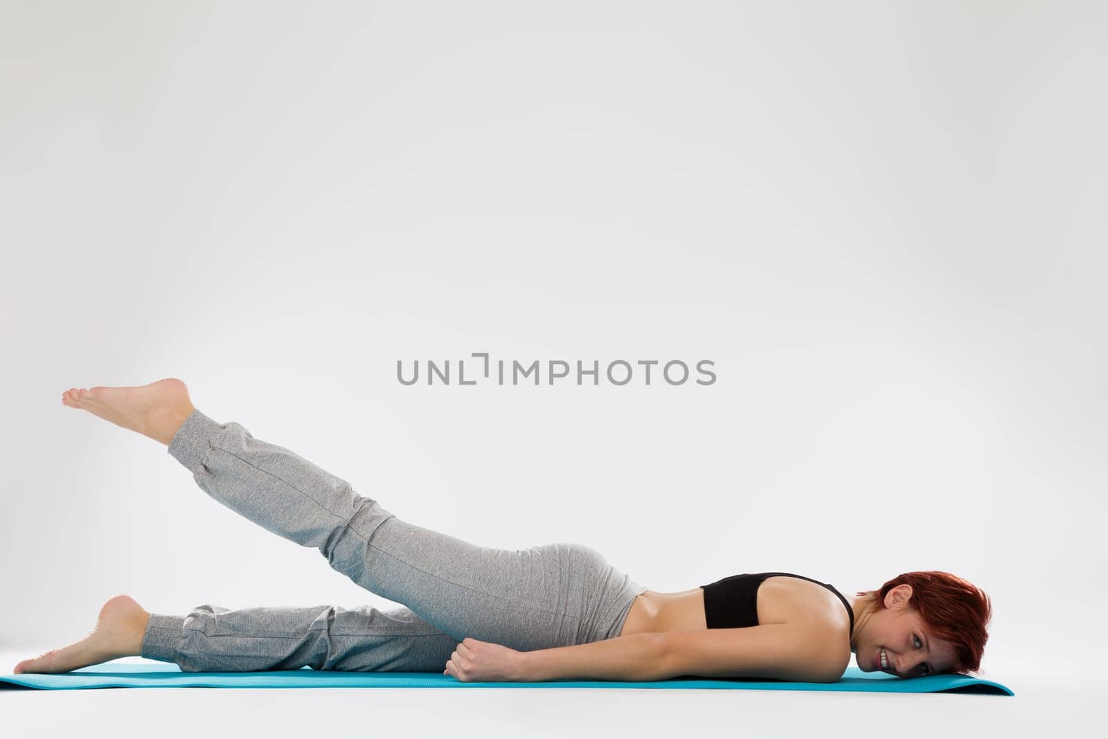 Young woman in fitness exercises trains her legs