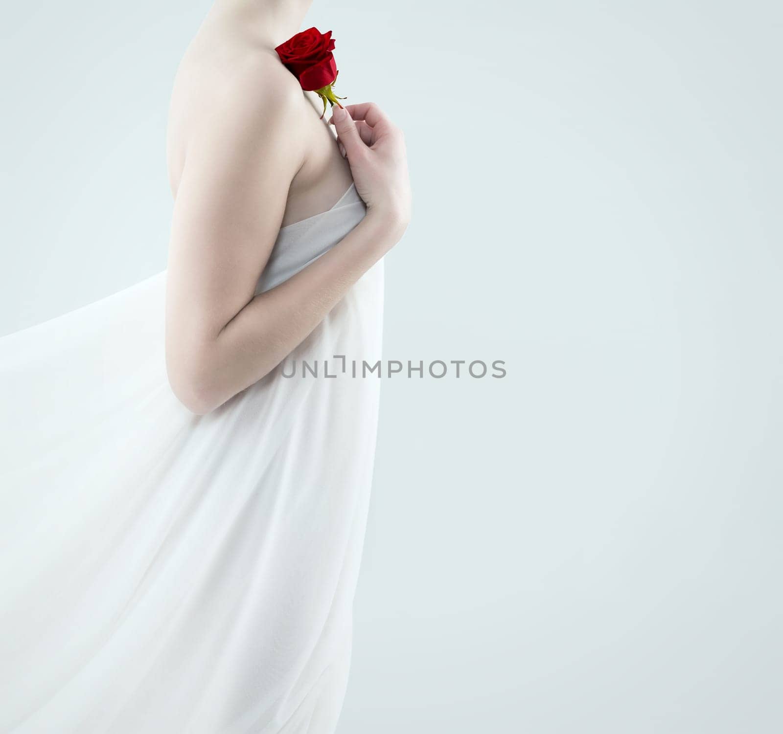 Young woman wrapped in scarves holds Red Rose to her shoulder
