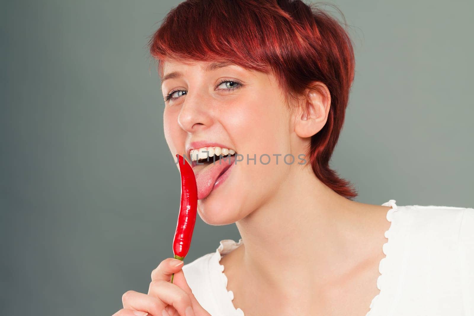 Young red-haired woman licks red pepperoni