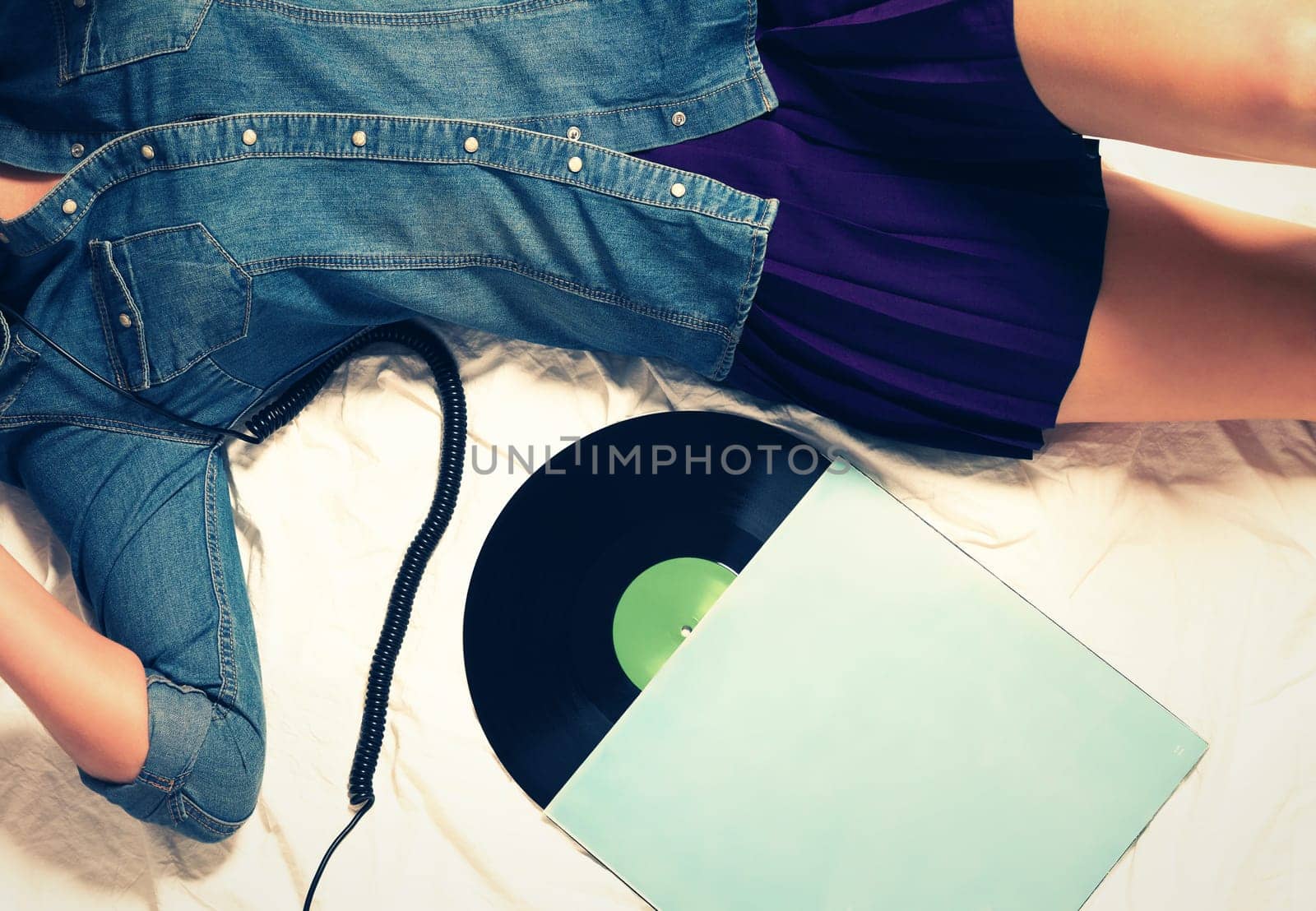 Young reclining woman in jeans shirt and short skirt next to a record