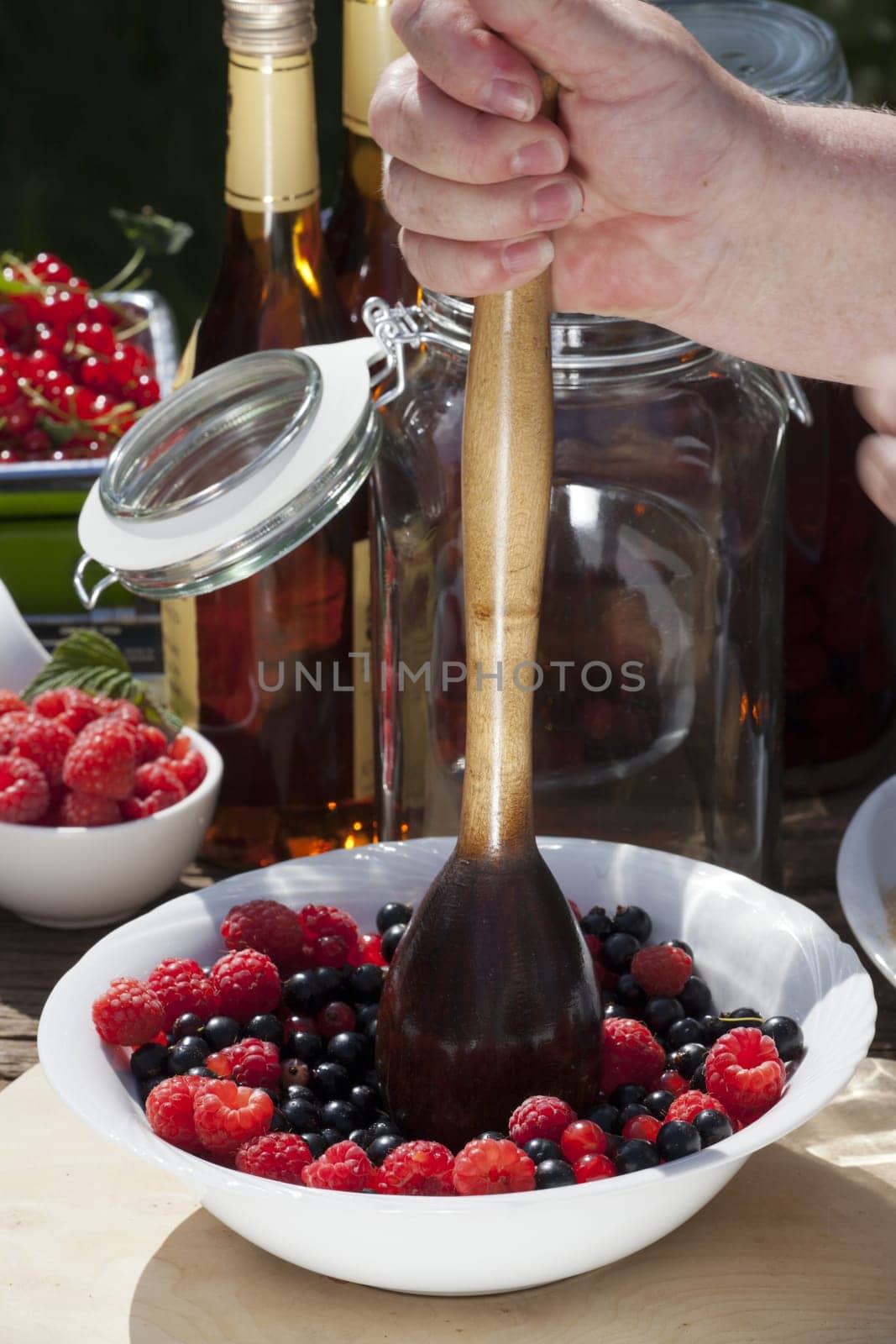 Make your own blackcurrant liqueur,Step 1,chop currant and raspberry fruits with a wood masher