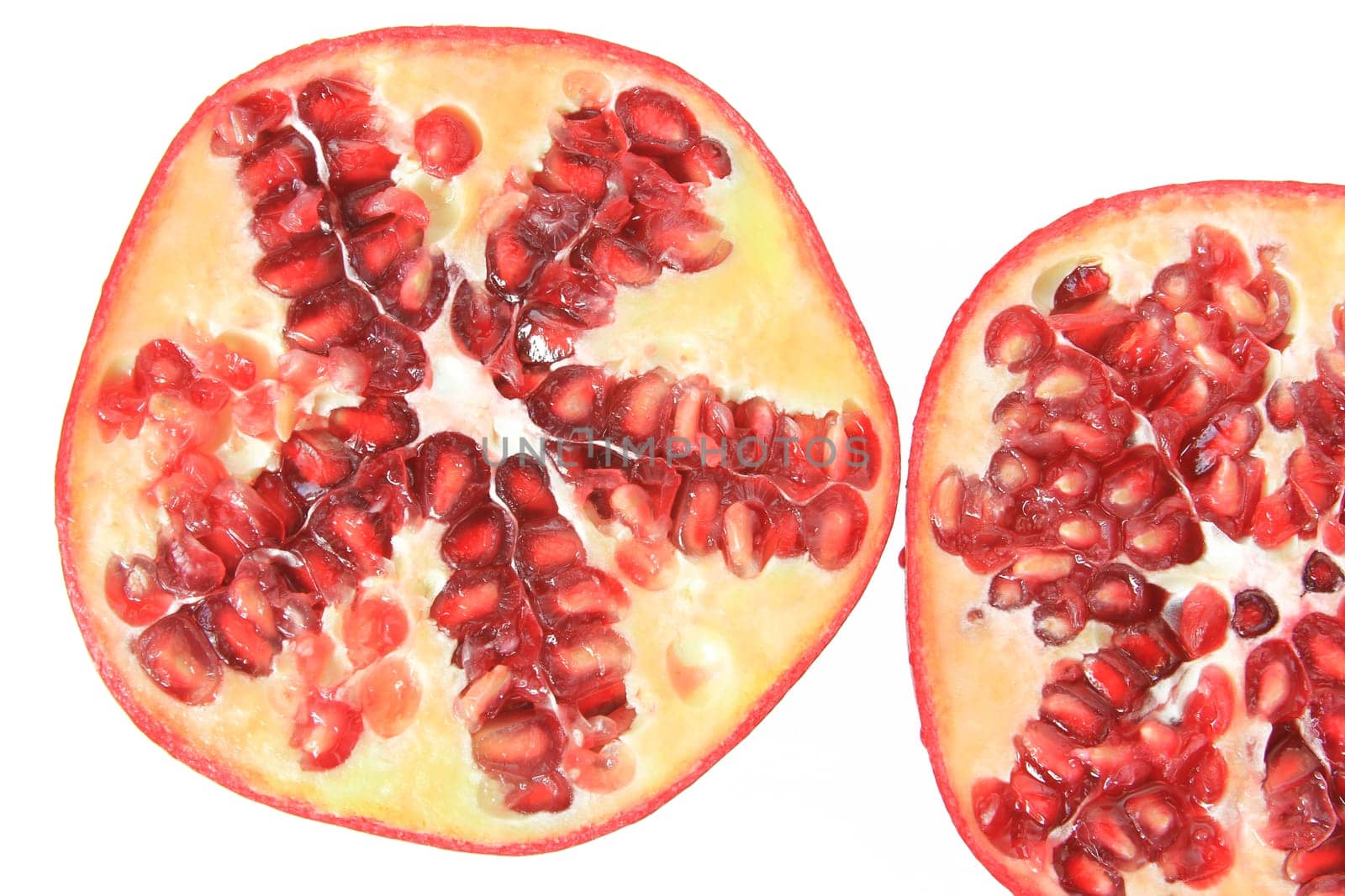 Ripe,halved pomegranate (Punica granatum) exposed against a white background