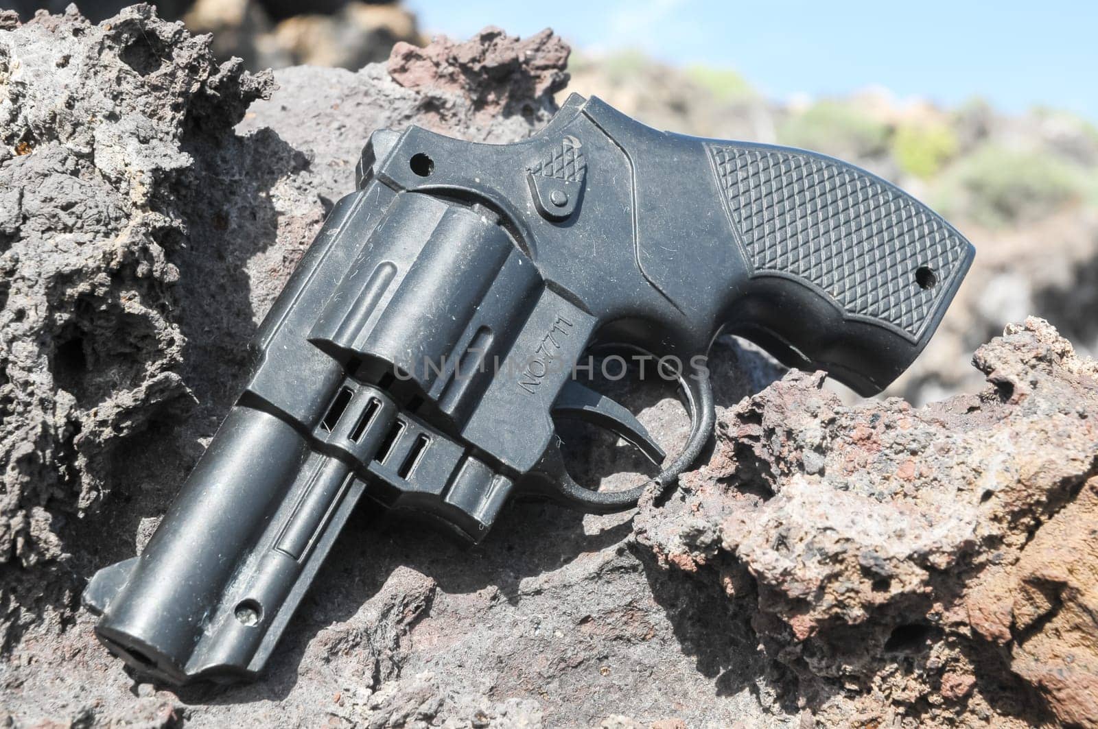 Plastic Revolver Gun Toy on the Volcanic Rocks