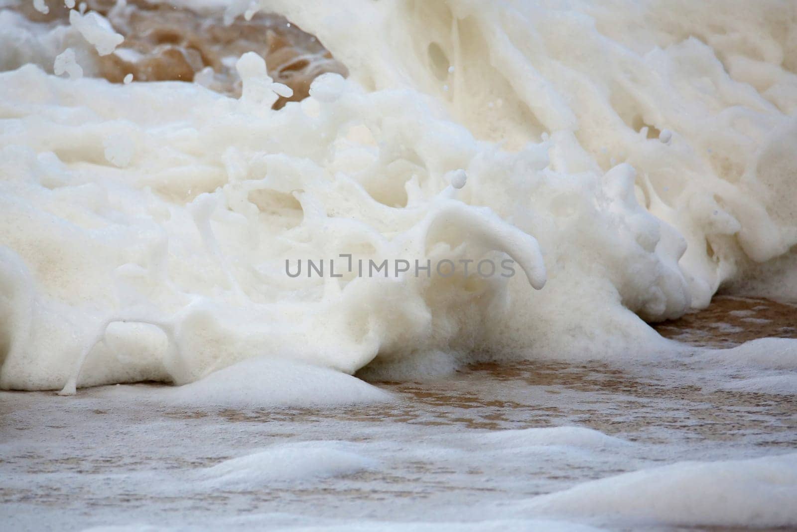 Faomy sea water splashing onto the sandy beach