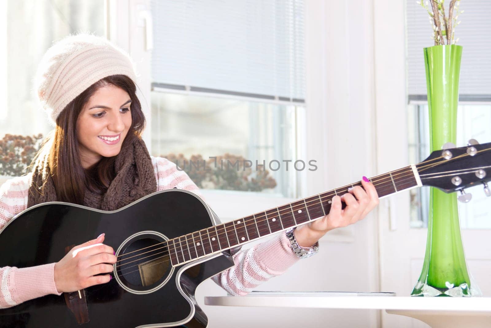 girl playing the guitar next to the table and smiling