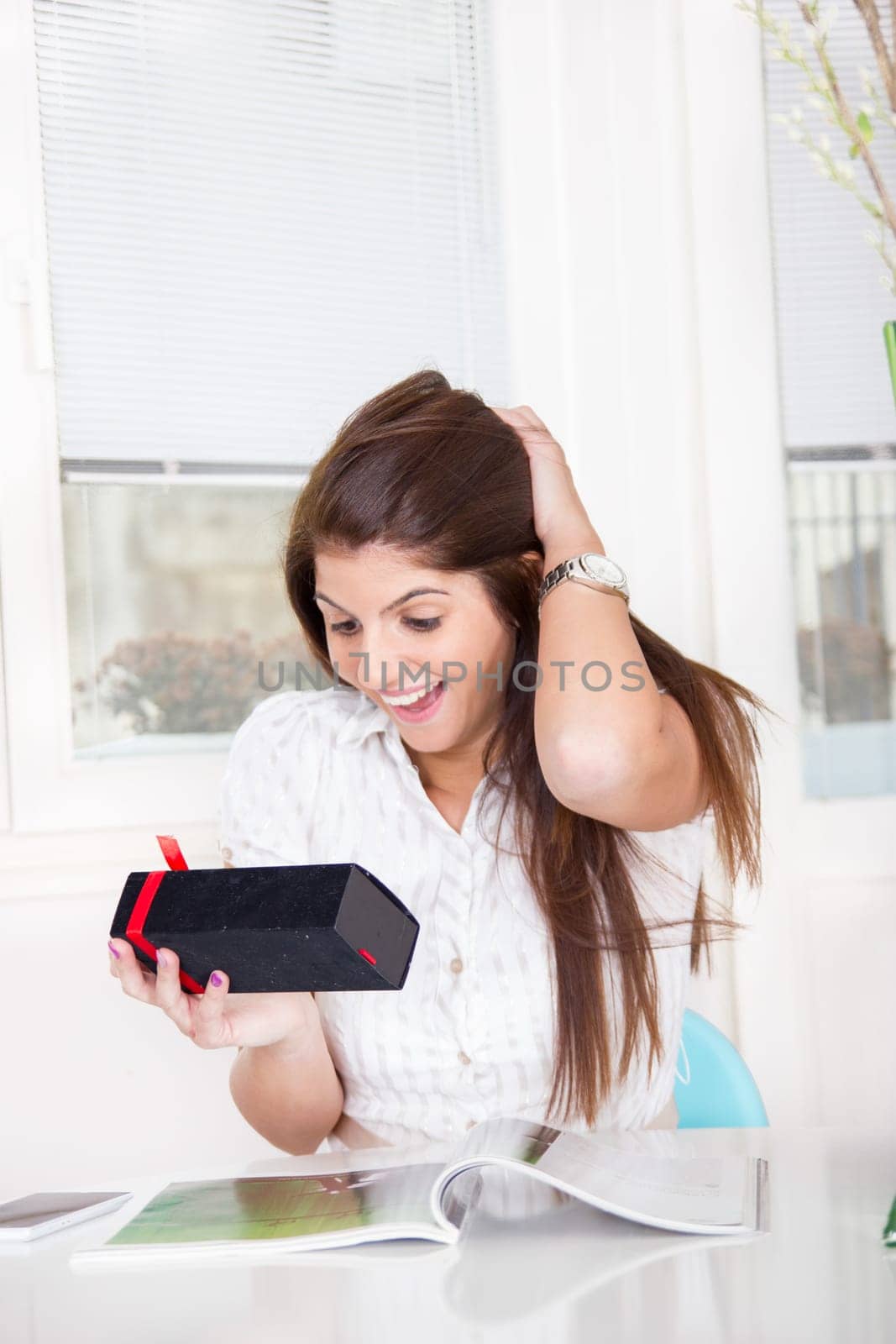 pretty surptised girl in white shirt opens the gift at home