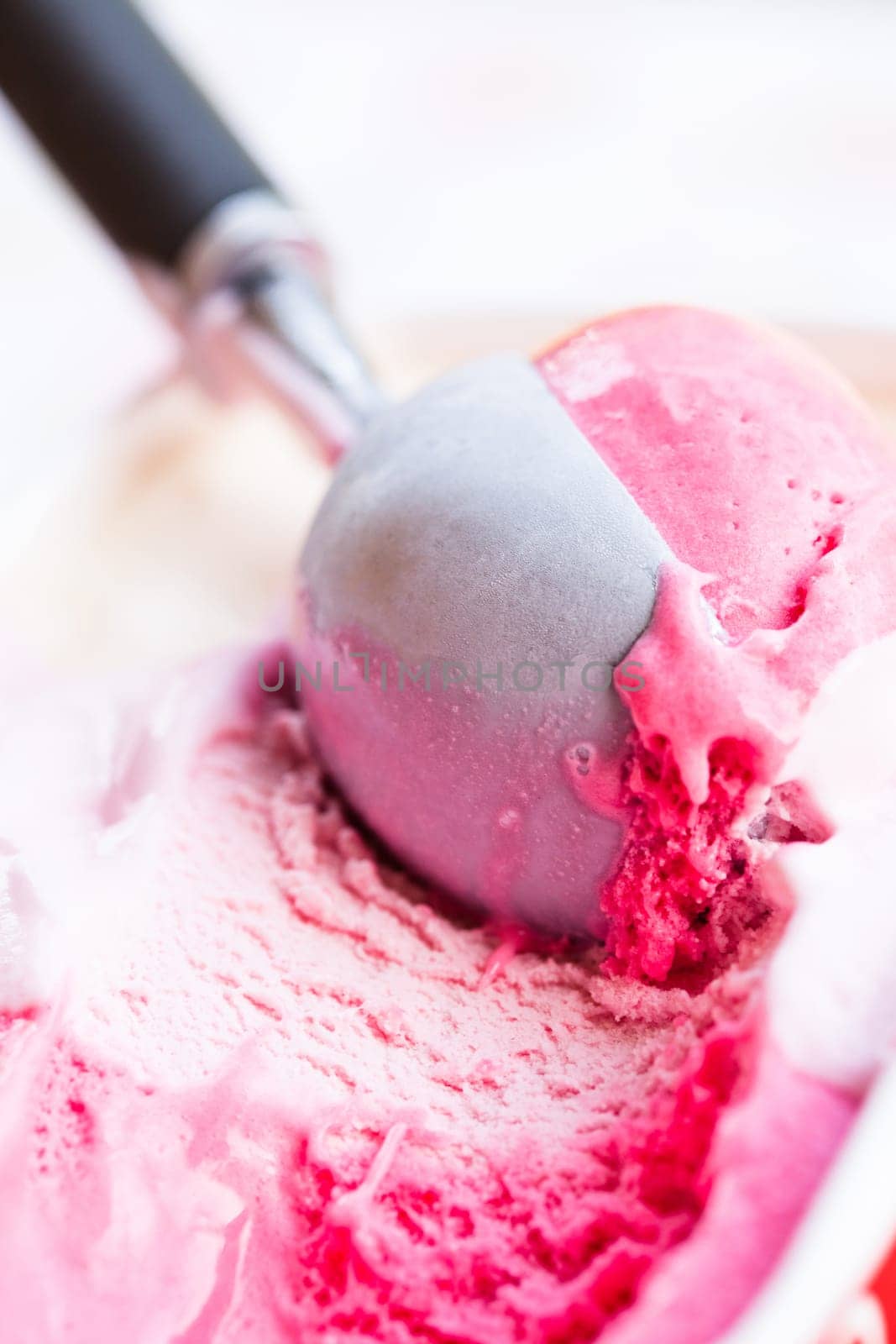 Closeup of raspberry ice cream and metal ice cream scoop