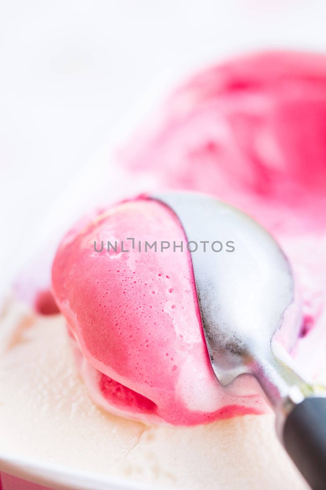 Closeup of raspberry ice cream and metal ice cream scoop