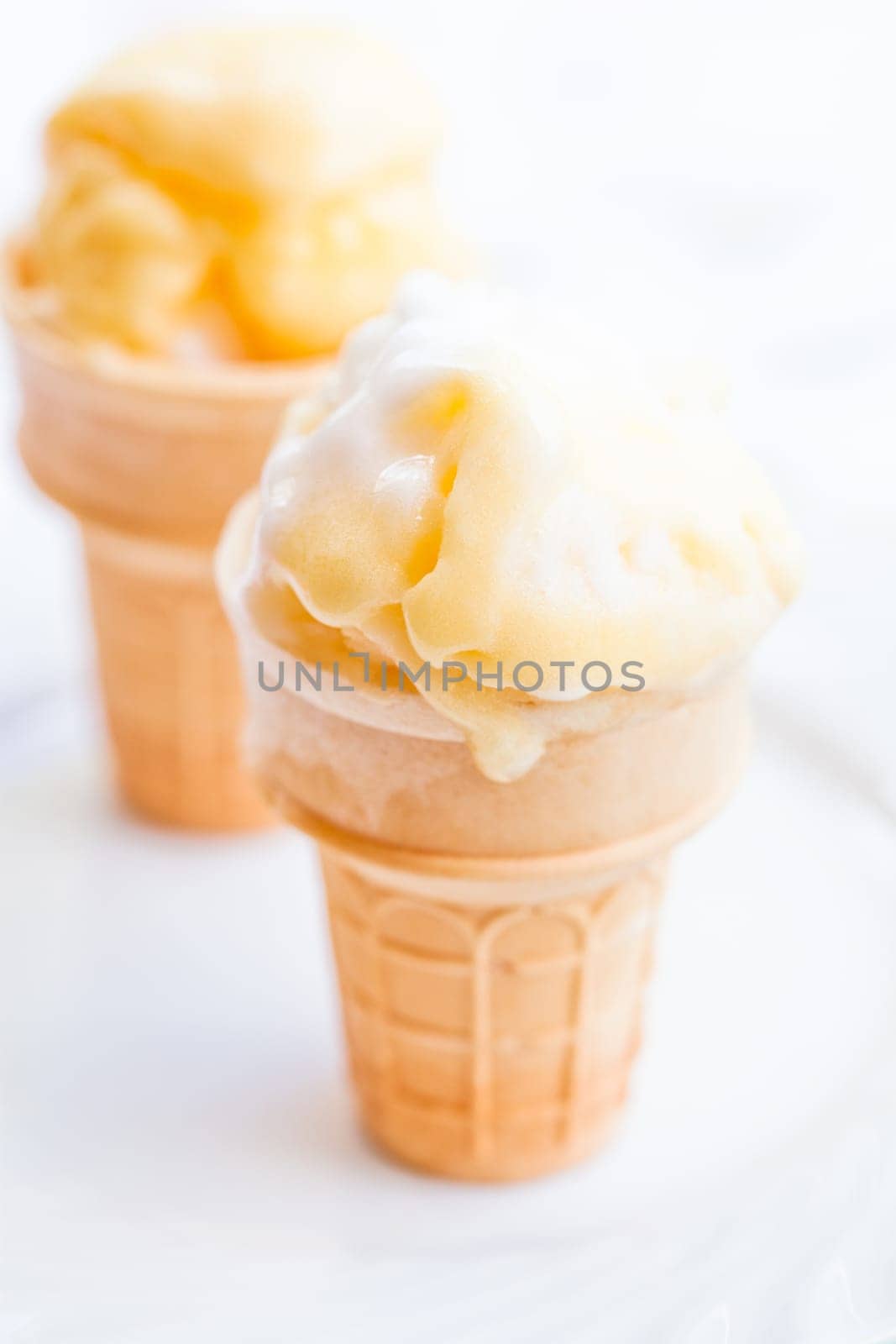 Closeup of two cones of mango ice cream on light background