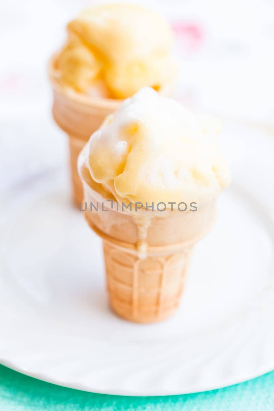 Closeup of two cones of mango ice cream on white plate