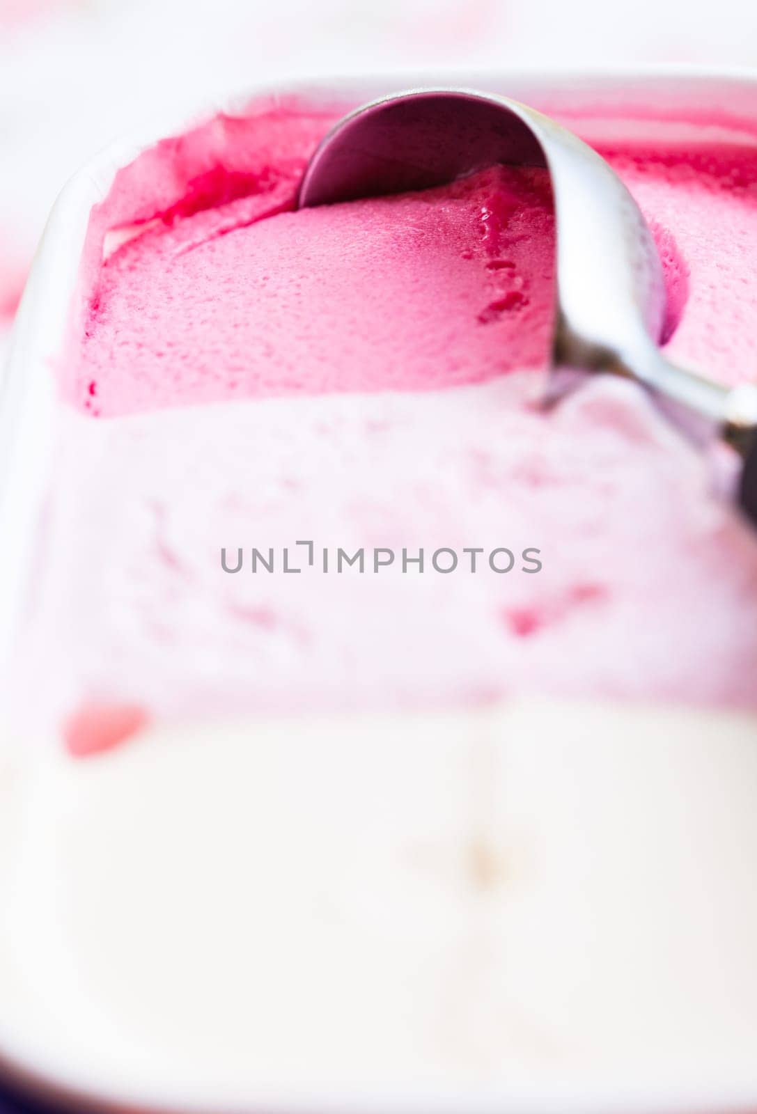 Closeup of raspberry ice cream and metal ice cream scoop