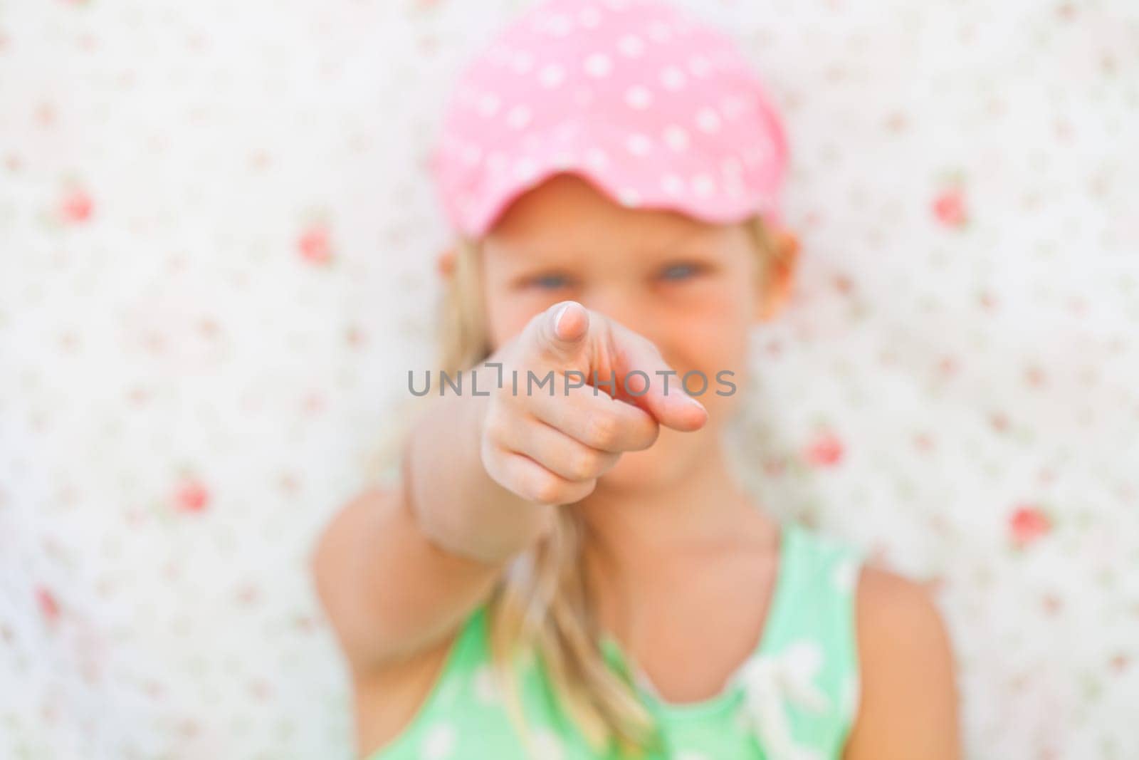 Focus on hand of cute young pointing with finger and looking ahead