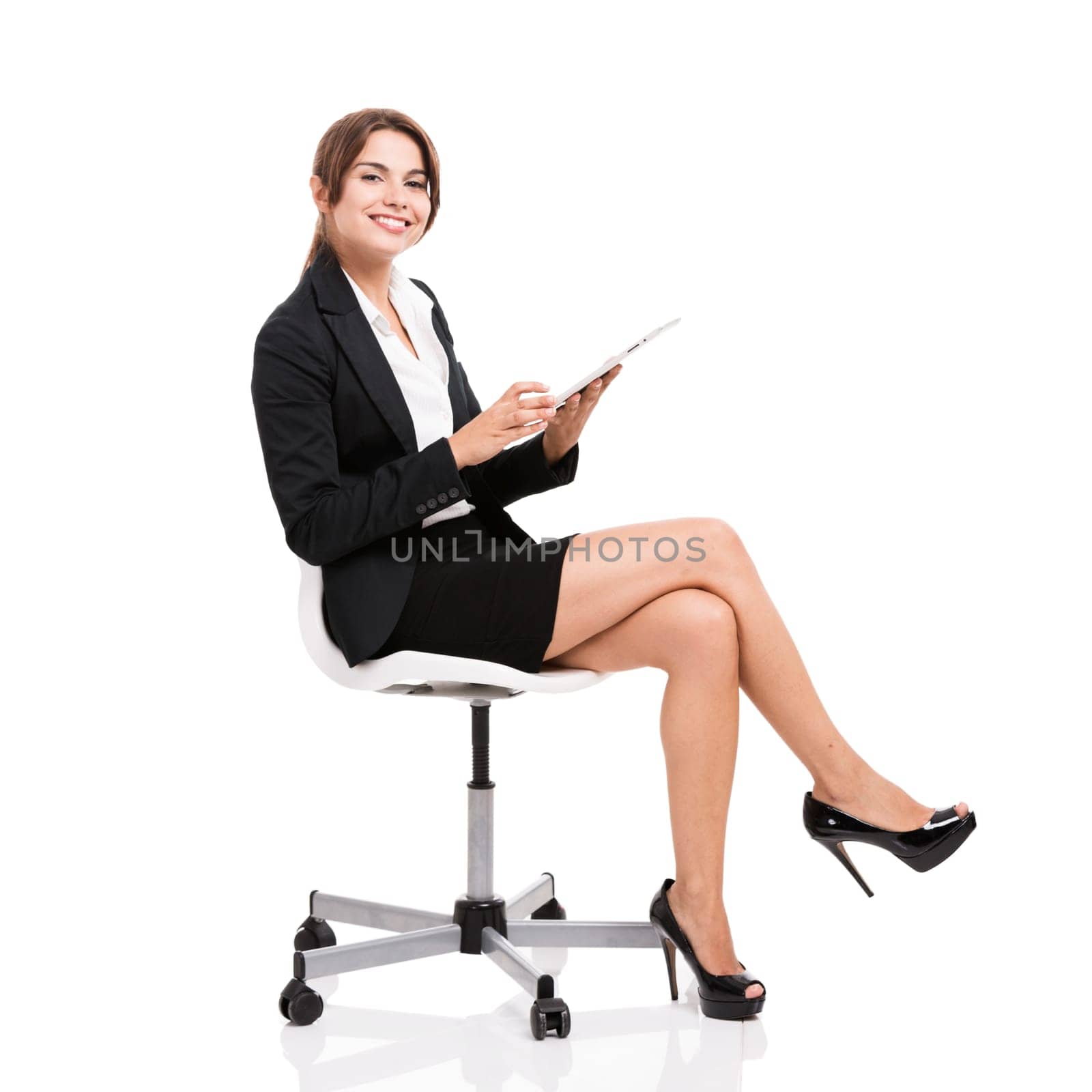 Happy business woman sitting on chair working with a tablet, isolated over white background