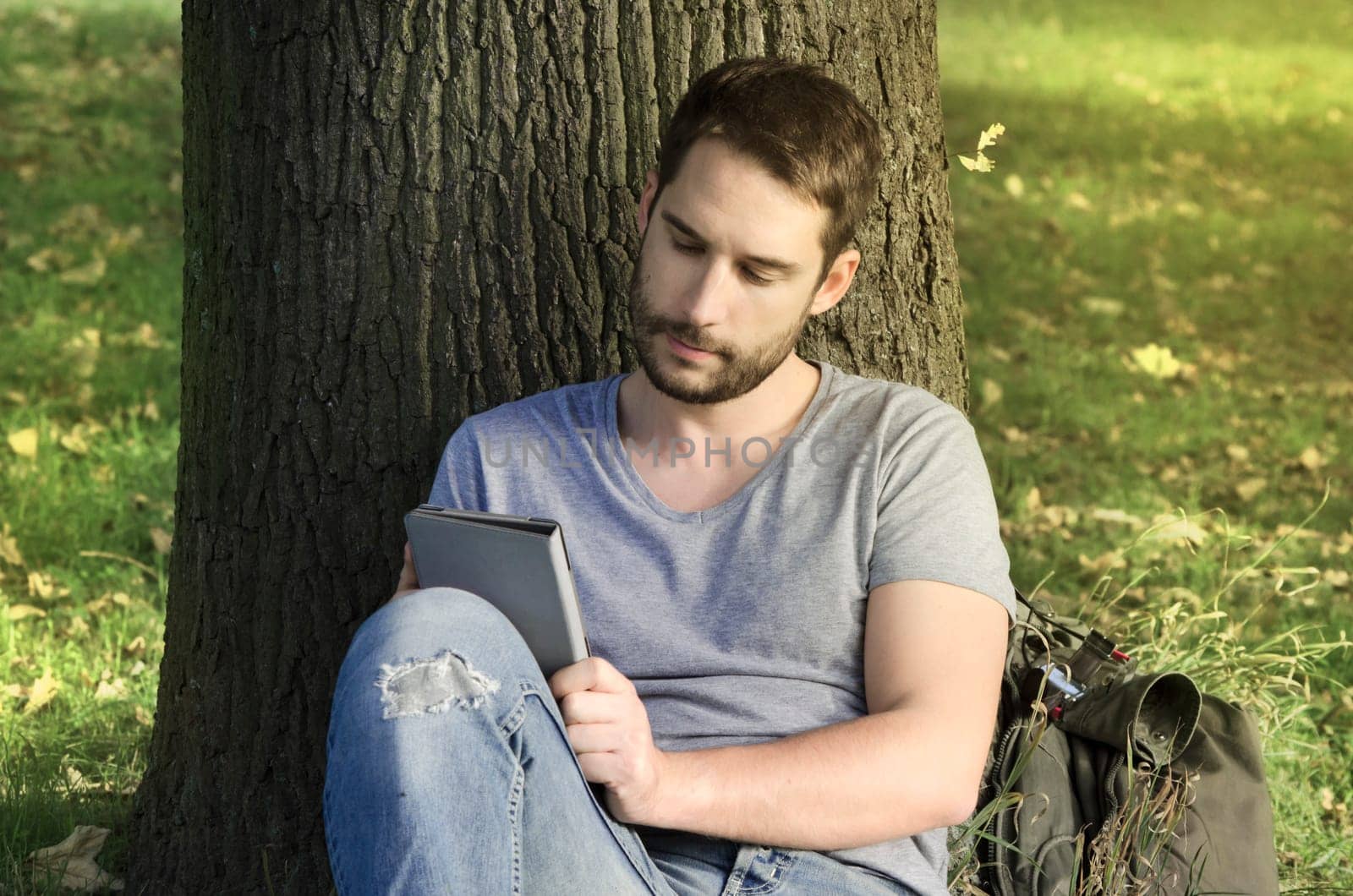 Young man reading e-book in the nature