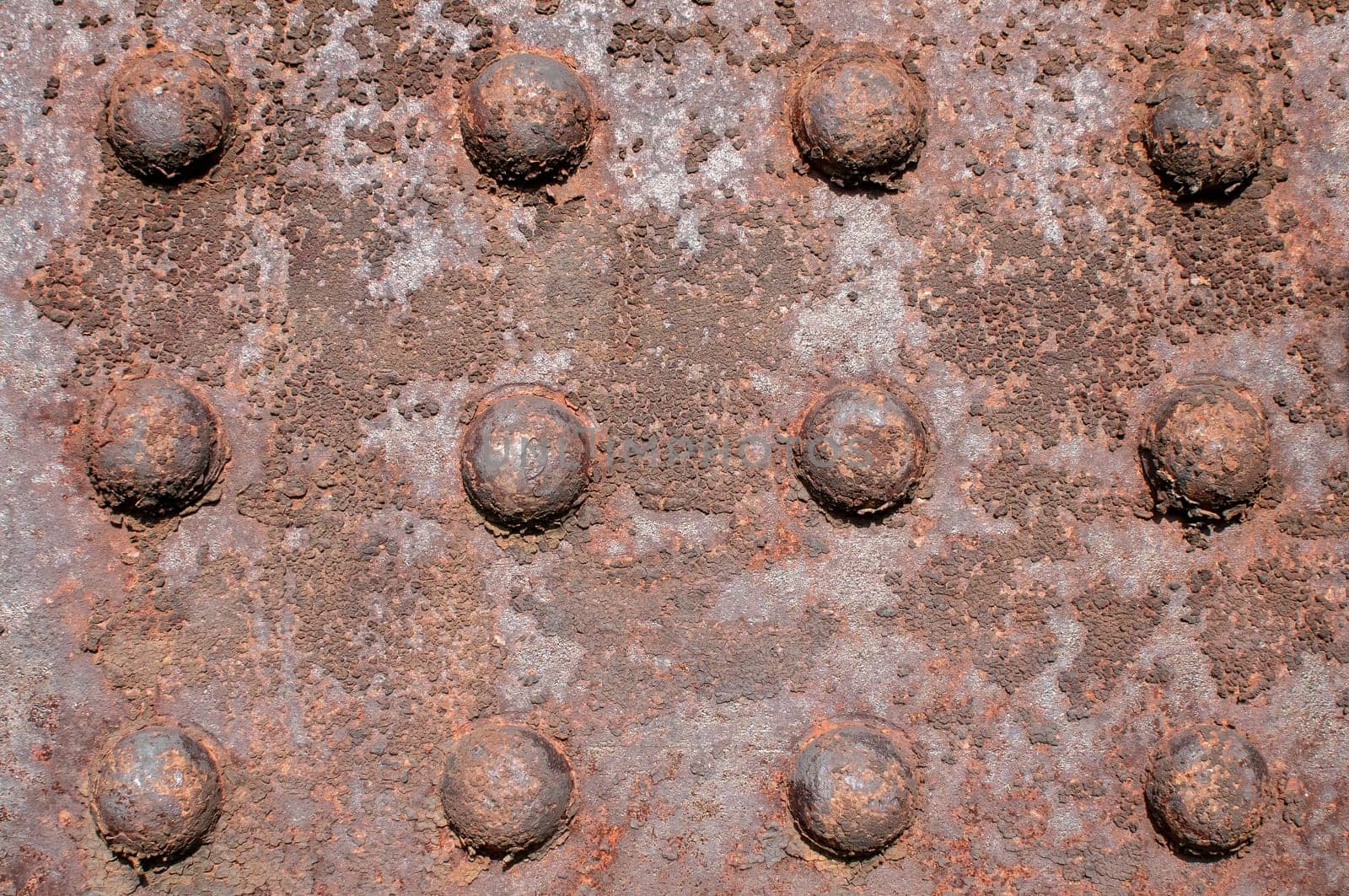 Weathered rusty iron element with centennial rivets link as background