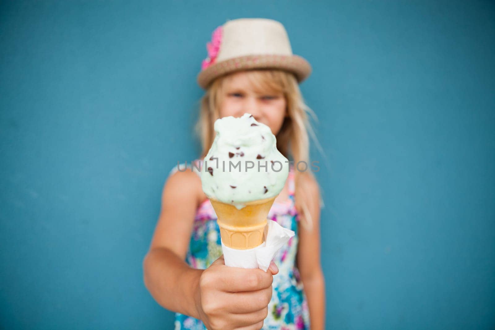 Closeup and focus on vanilla ice cream cone held by cute young girl