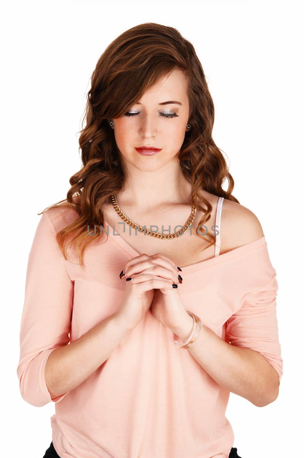 A lovely young woman standing for white background with her hands folded.and eyes closed, praying..