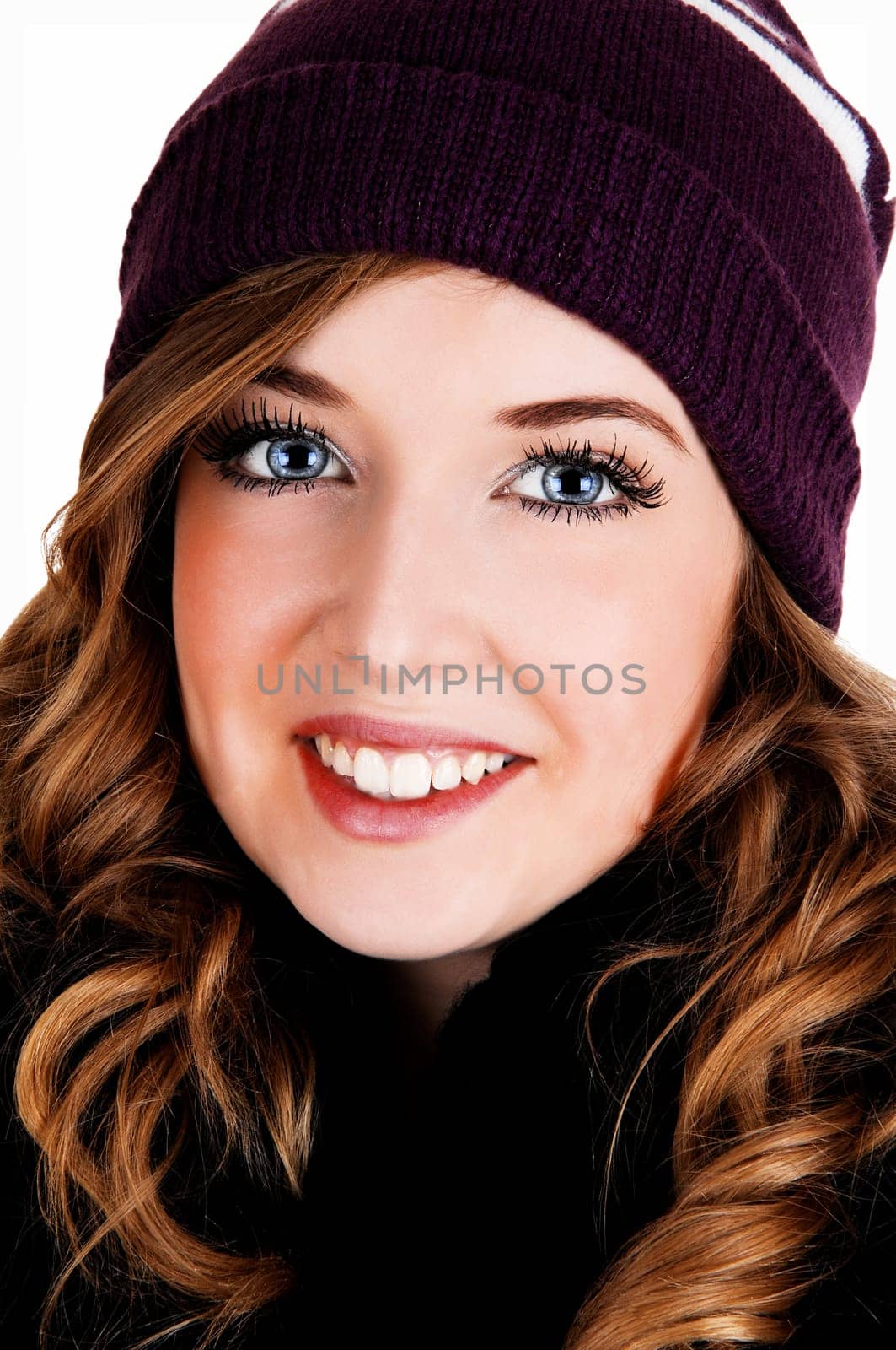 A closeup picture of a pretty young woman with nice blue eyes and curly.long hair with a knitted burgundy hat..