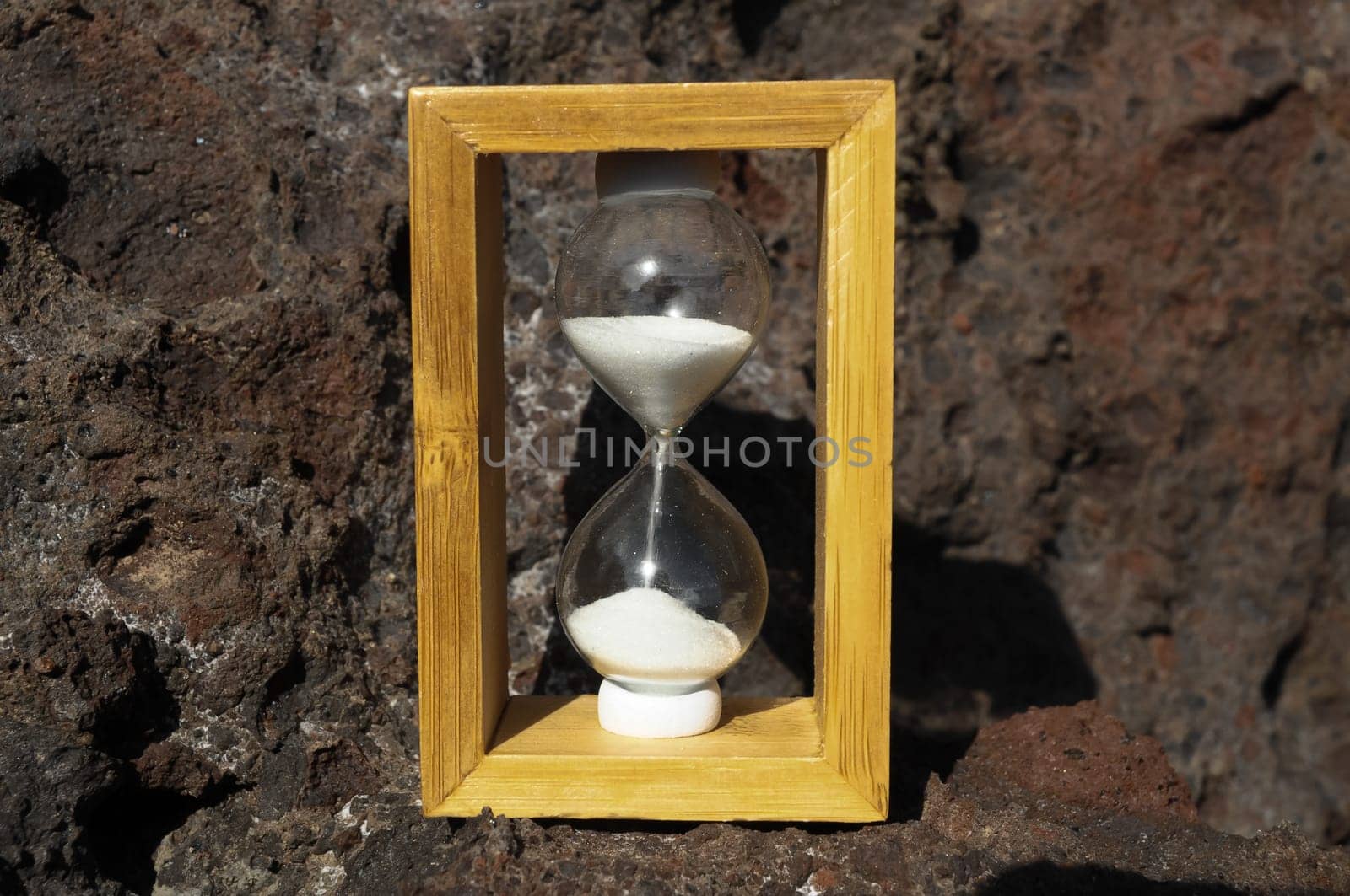 Time Concept White Sand Hourglass on the Volcanic Rocks